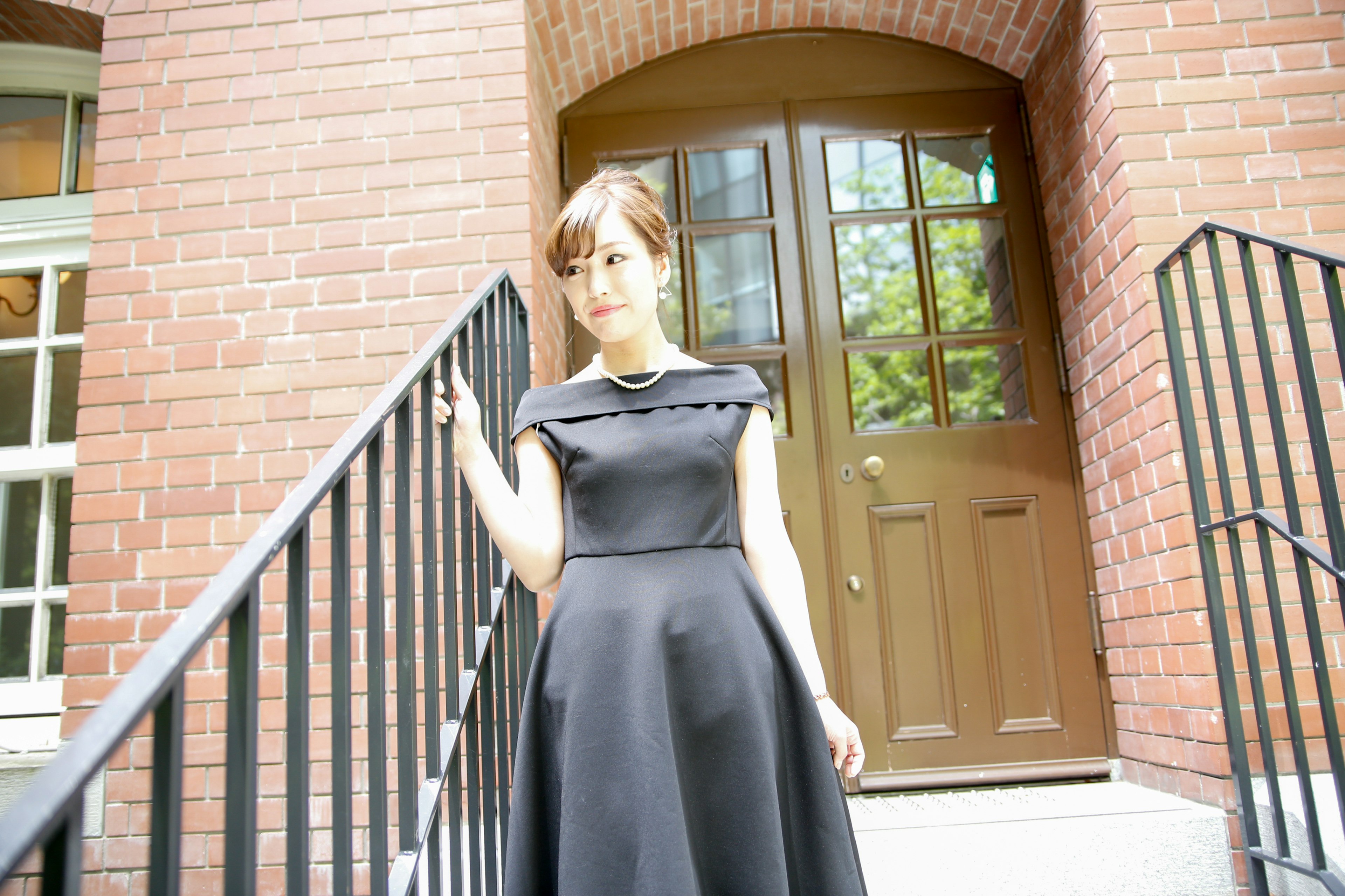 A woman in a black dress walking down the stairs of a brick building