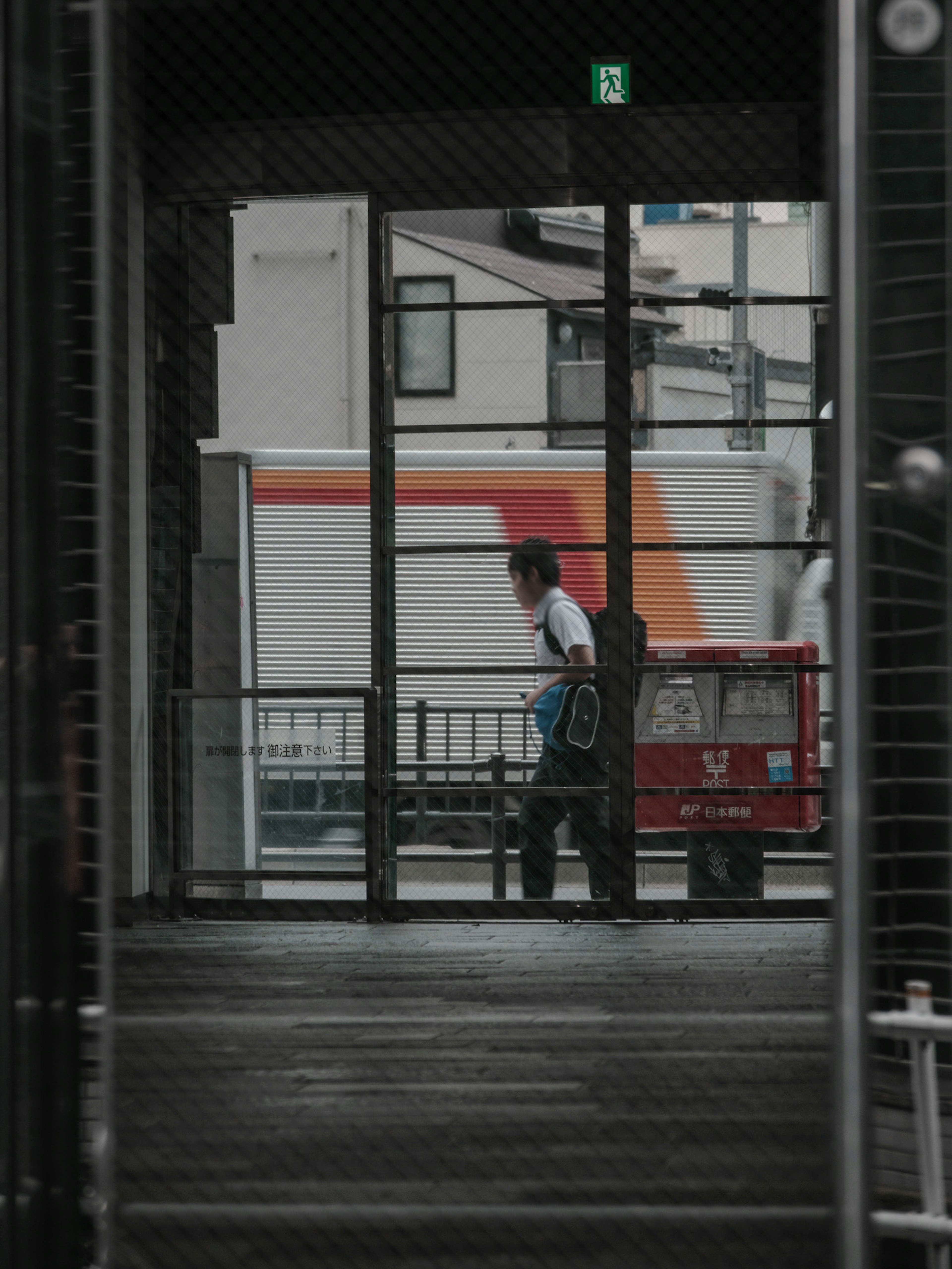 Un homme marchant à l'extérieur devant des portes en verre avec un camion en arrière-plan