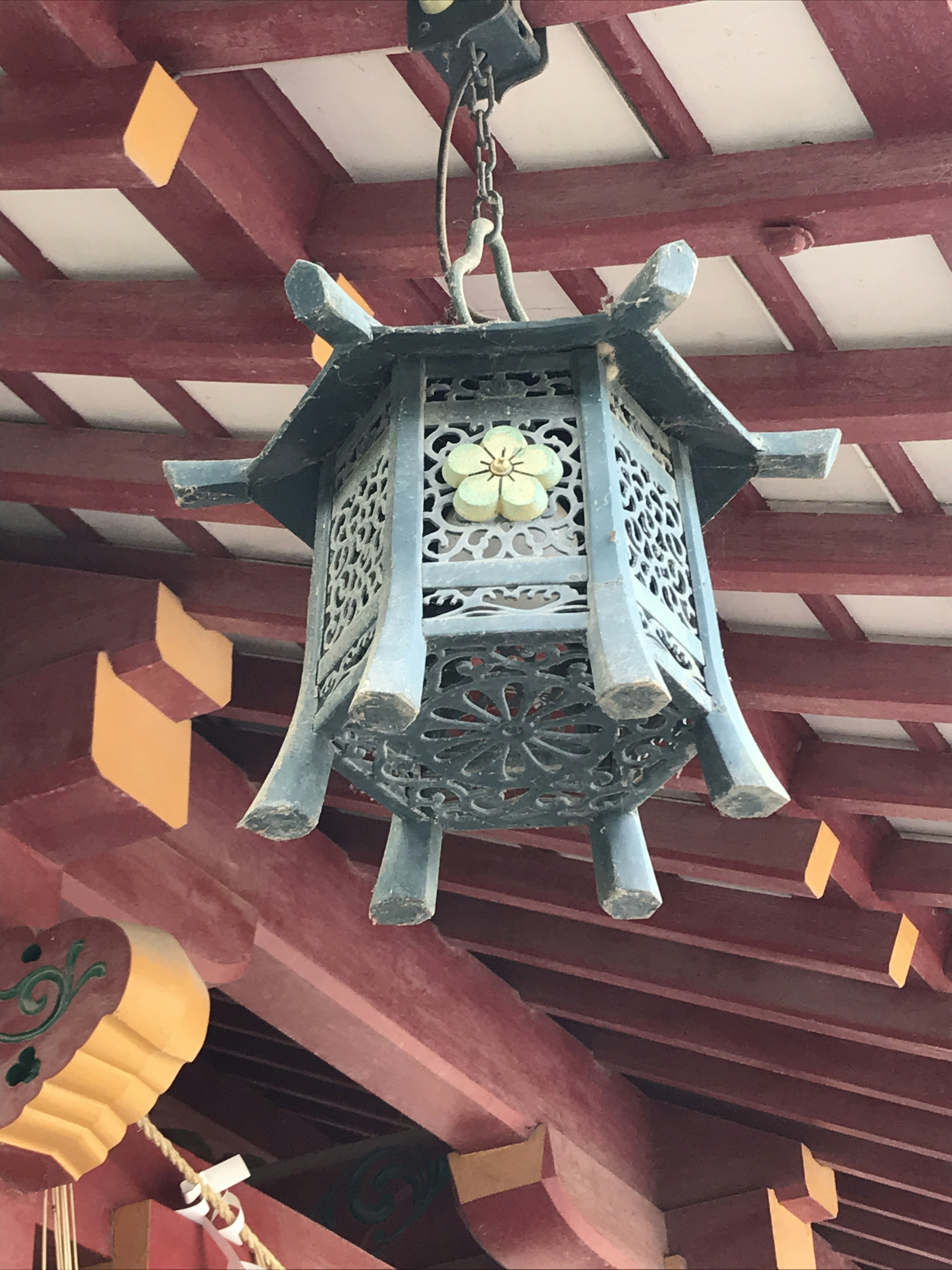 Decorative lantern hanging from a roof featuring blue metal with floral patterns