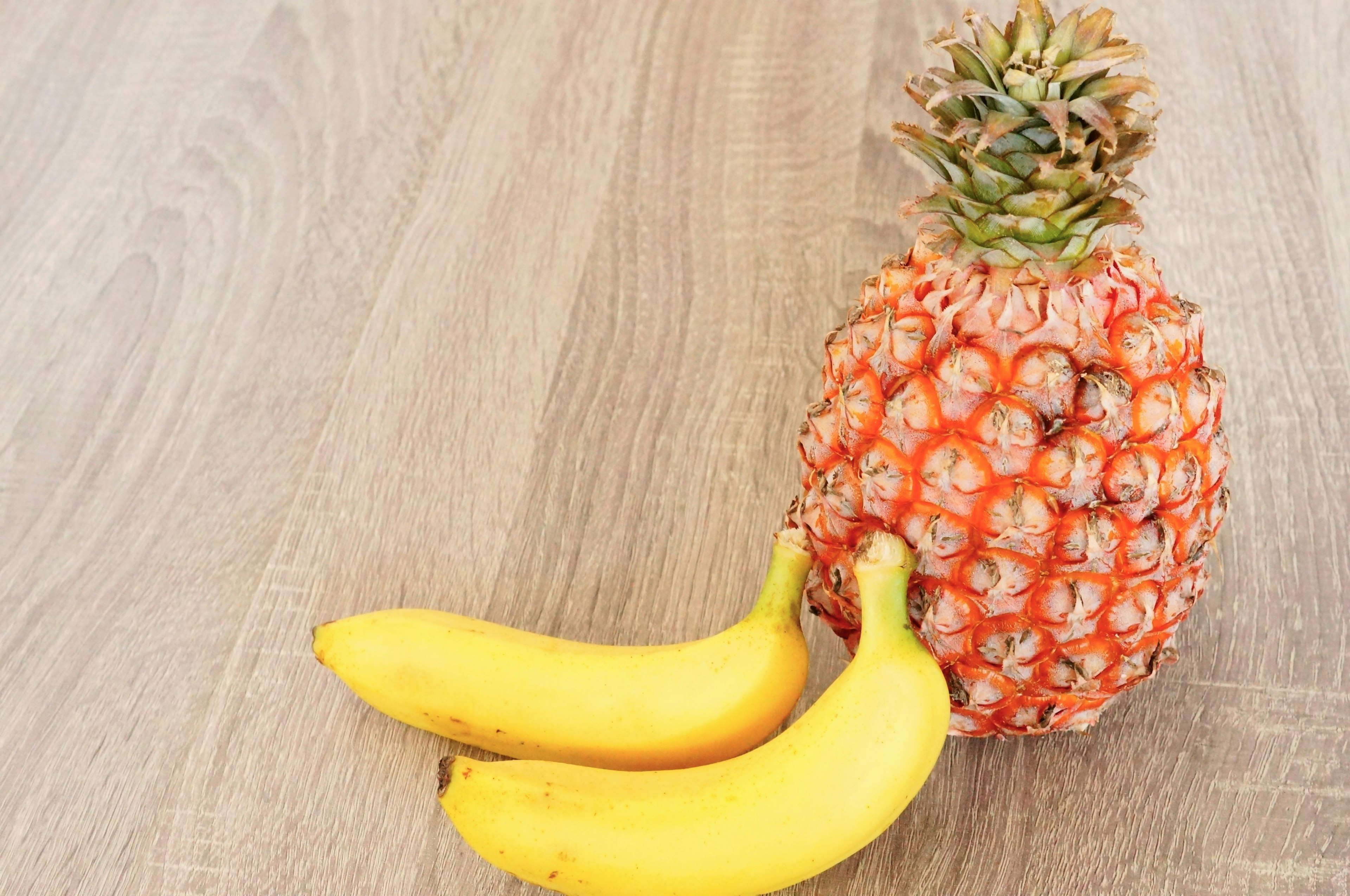 Combinazione di ananas e banane su un tavolo di legno