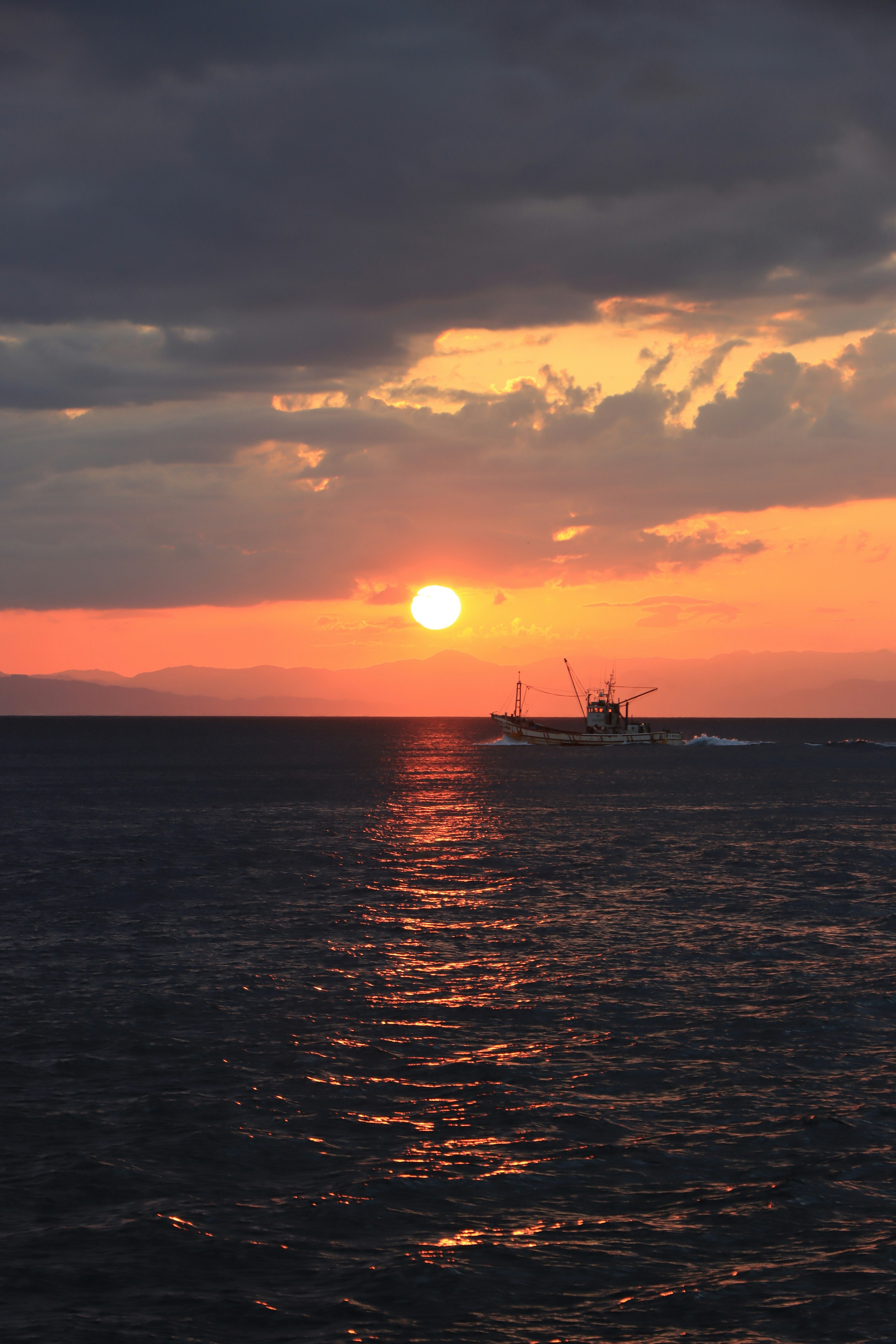 Tramonto sull'oceano con una barca in lontananza