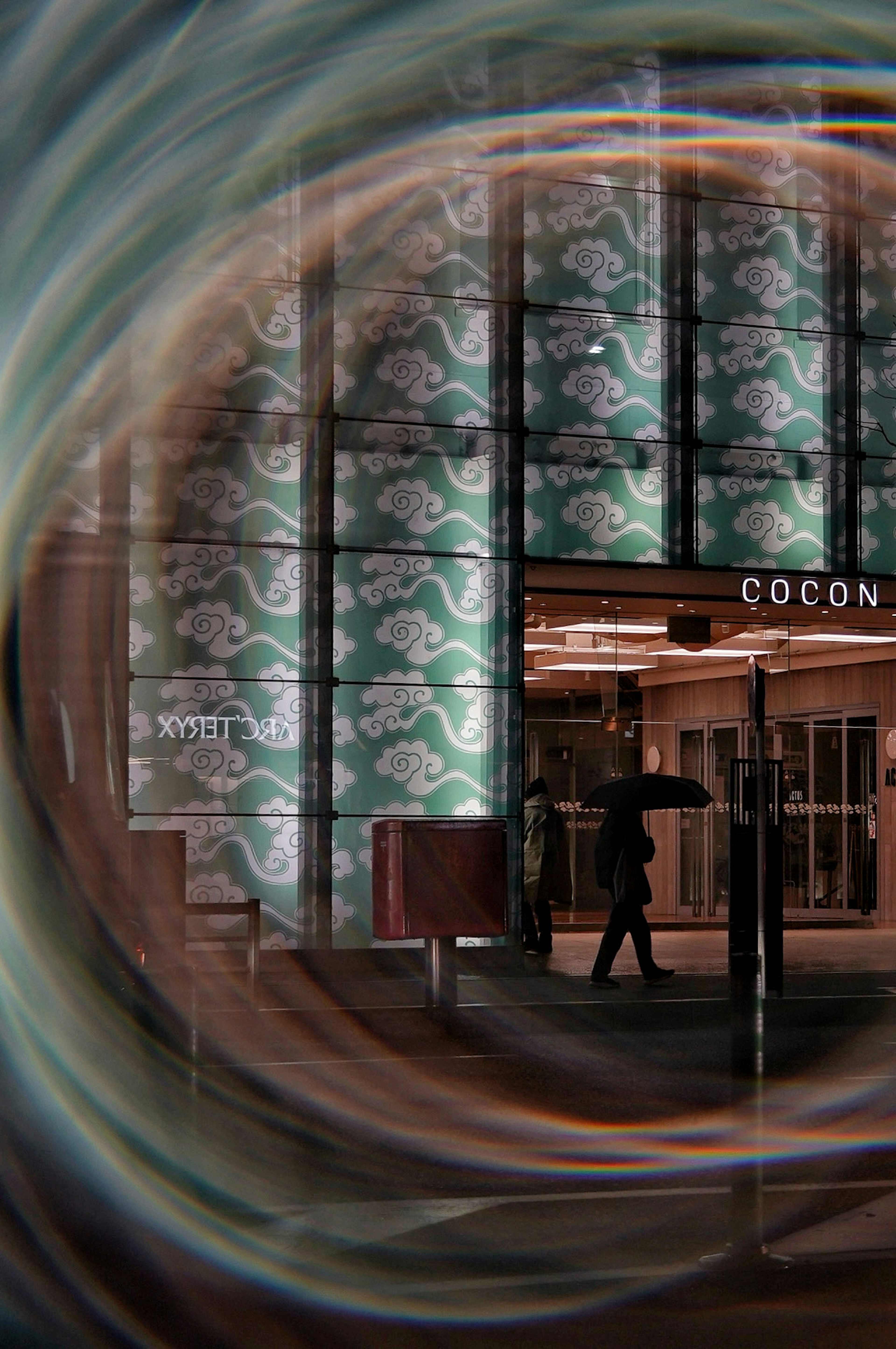 A person walking with an umbrella at the entrance of a building with colorful patterned walls