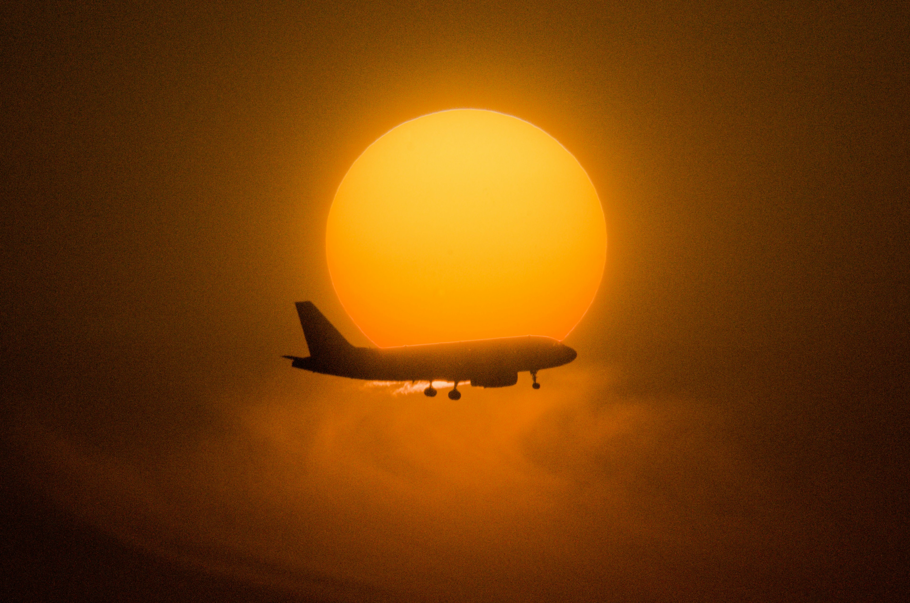 Silhouette di un aereo che vola contro un tramonto