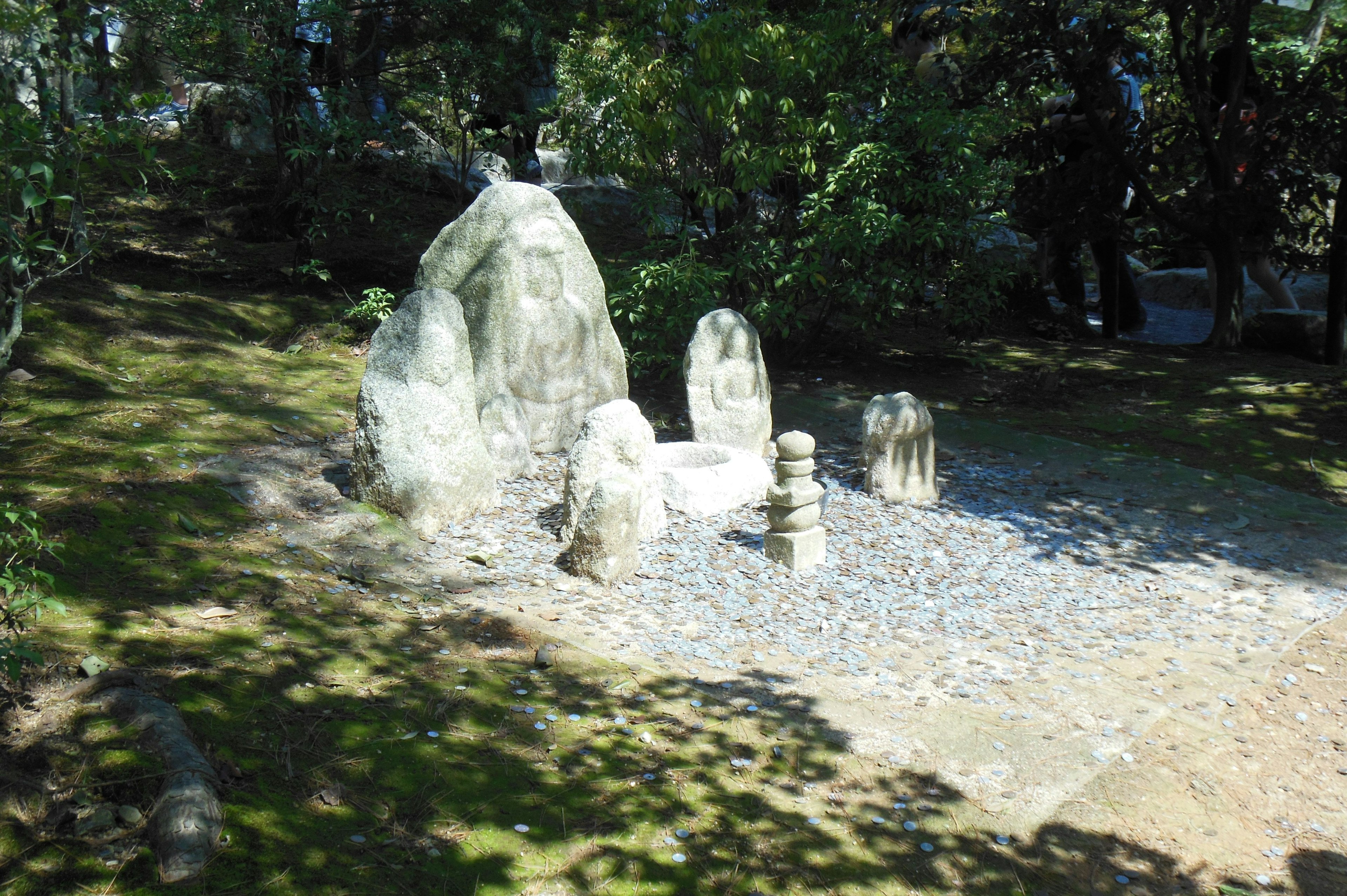 一個寧靜的公園場景，石雕被綠色植物環繞