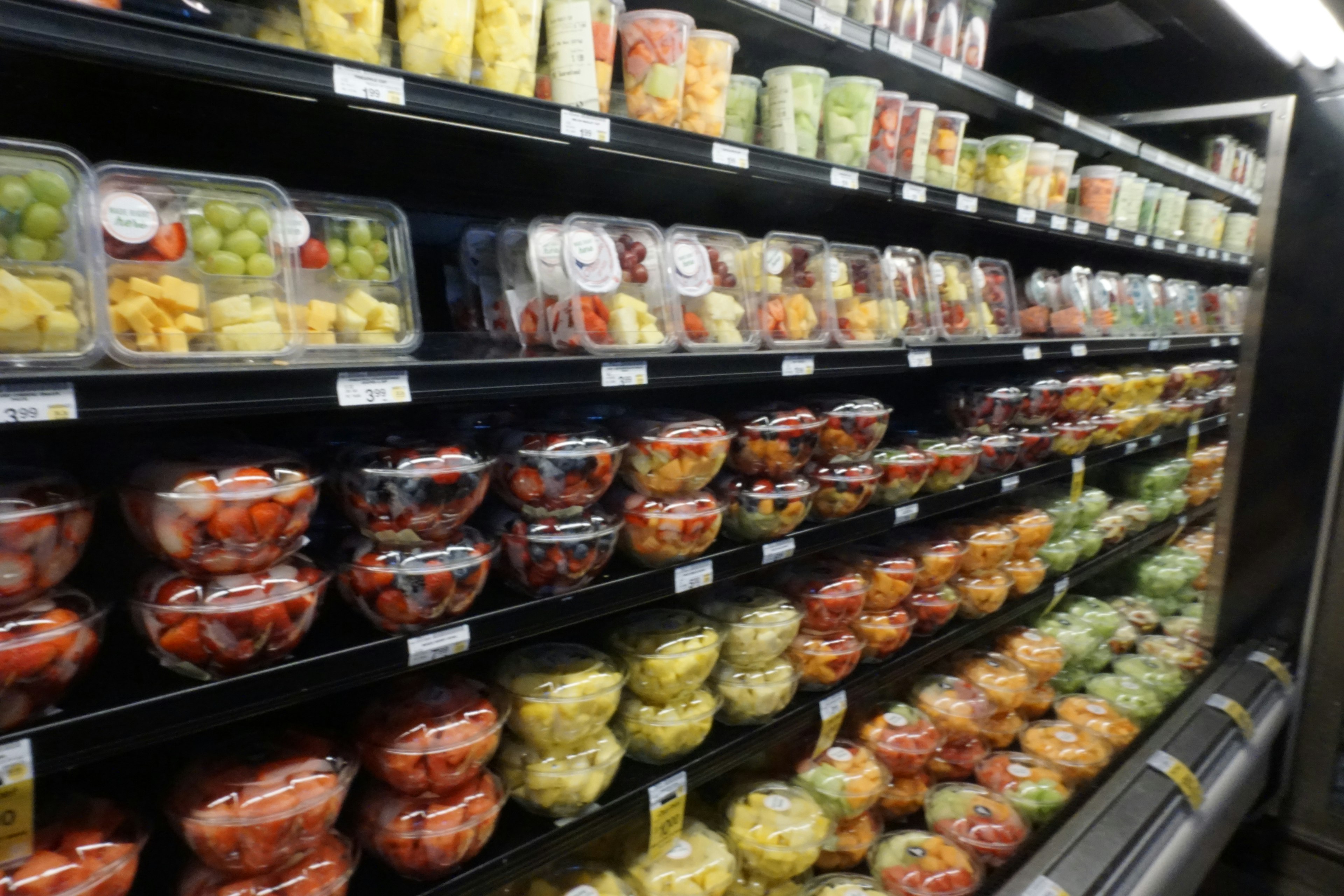 Colorful assortment of pre-packaged cut fruits displayed in a refrigerated aisle