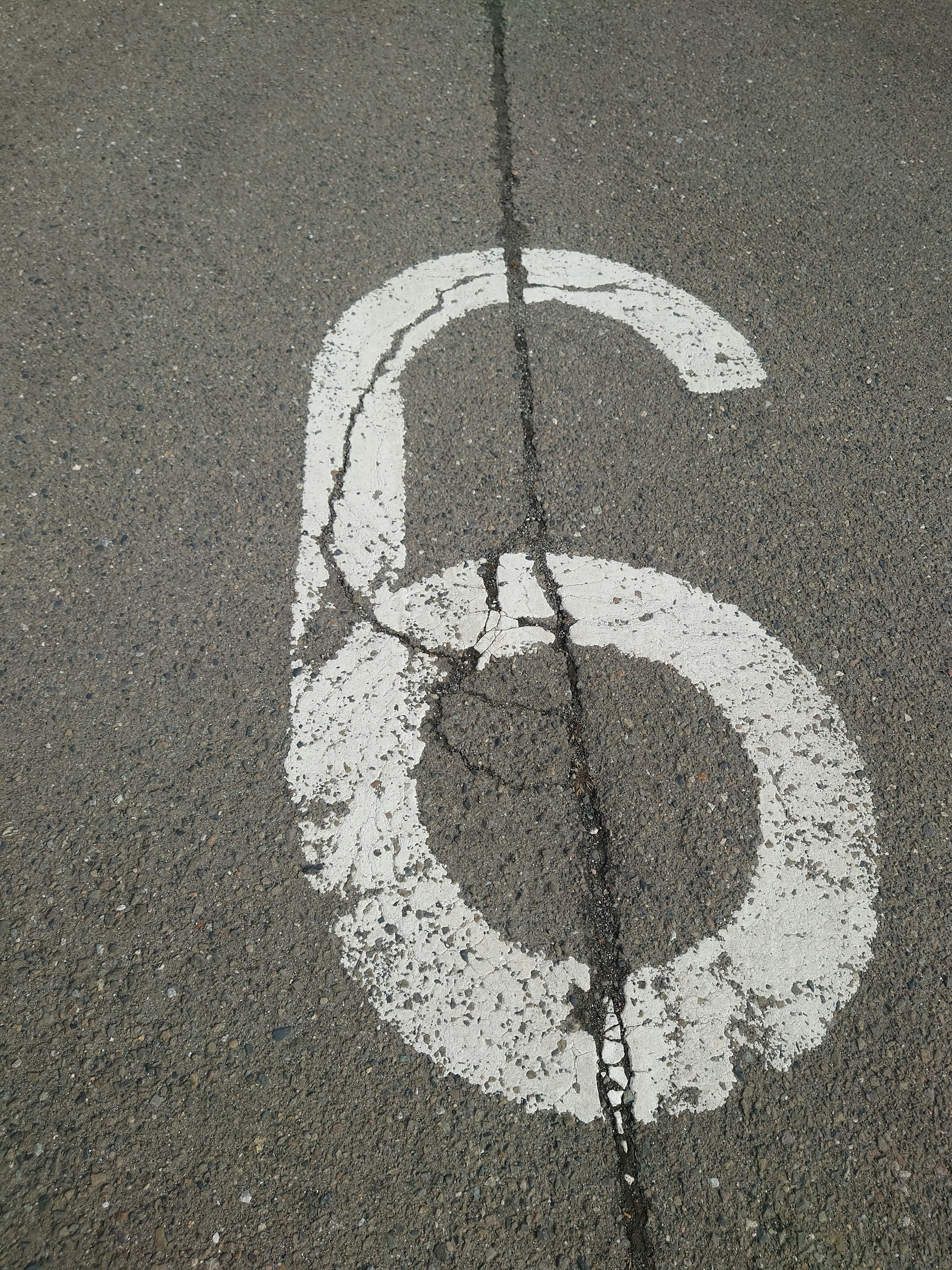 Close-up of a large white number 6 painted on asphalt