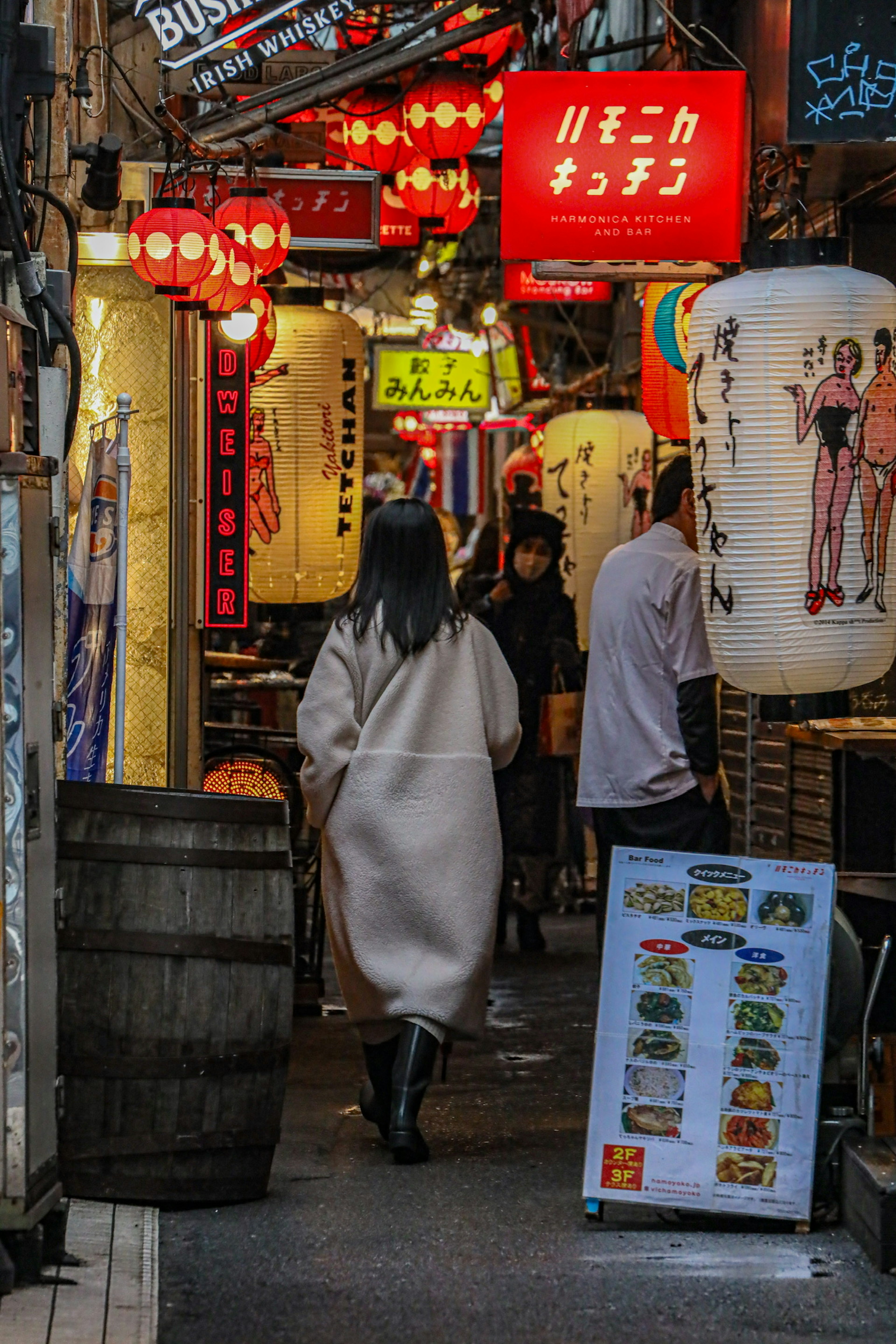 A woman walking through a vibrant Japanese alley adorned with colorful lanterns