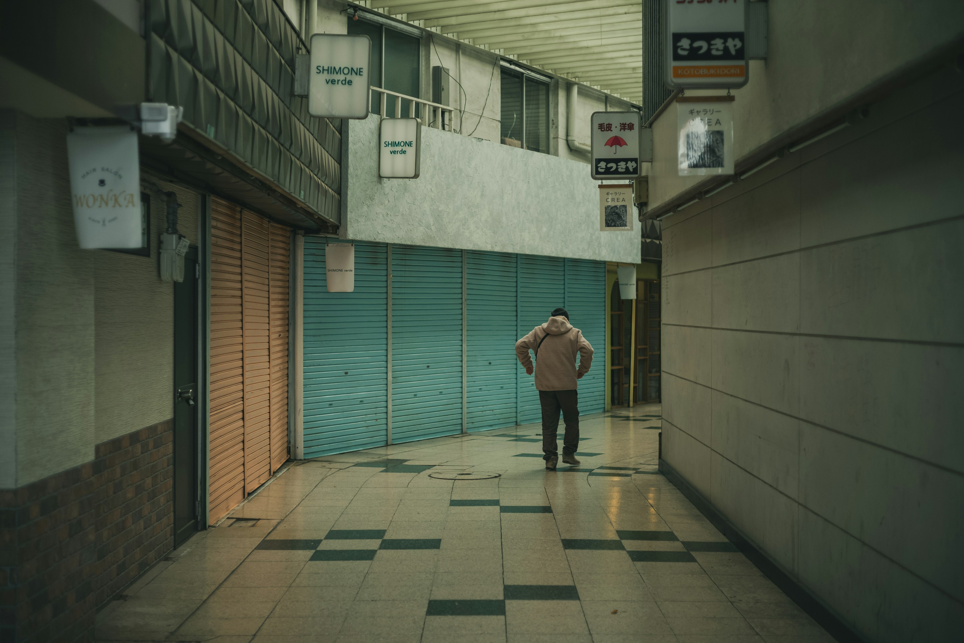 A man standing in a narrow corridor with closed shop doors