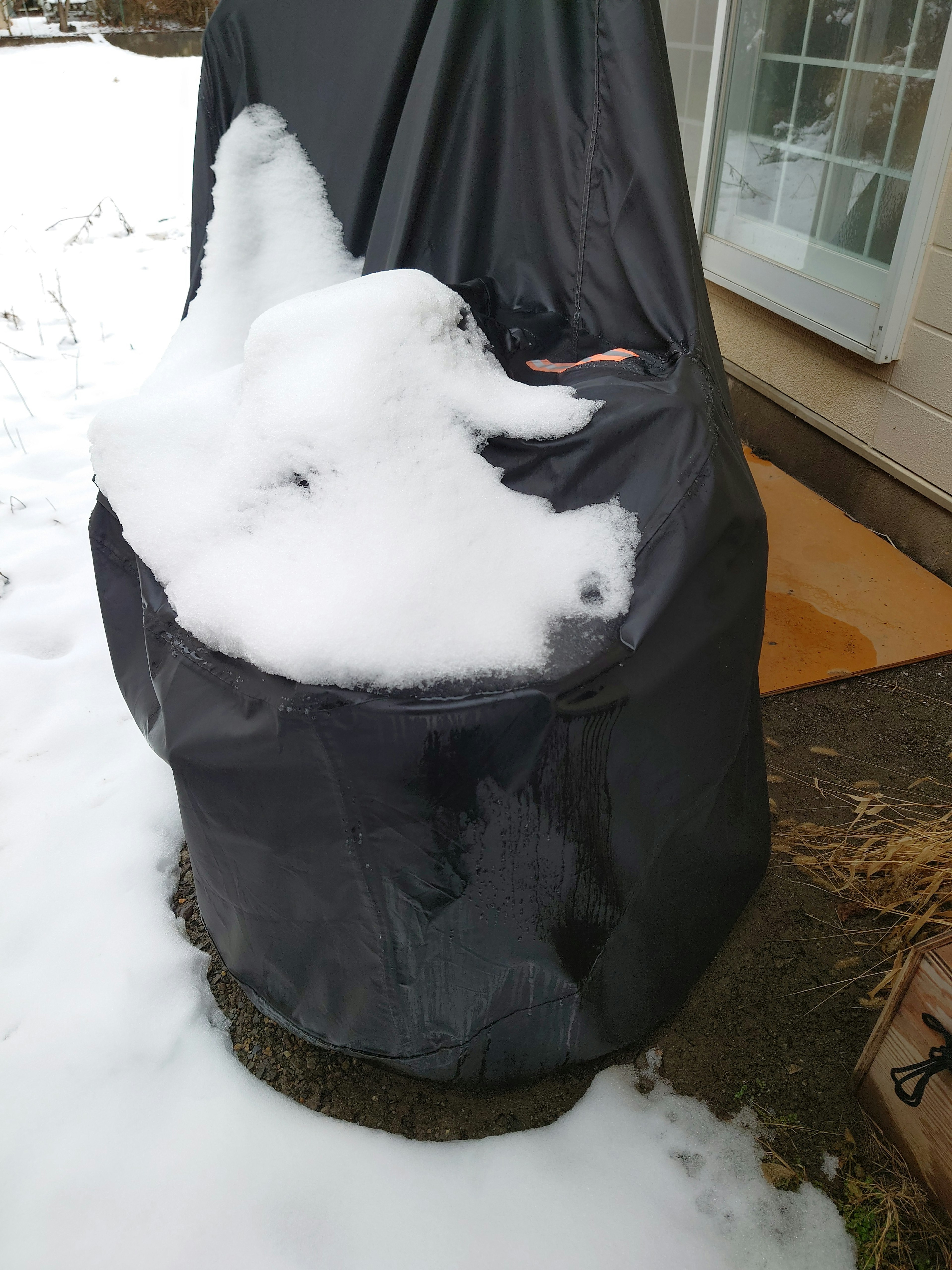 Una cubierta negra sobre una silla con acumulación de nieve en la parte superior