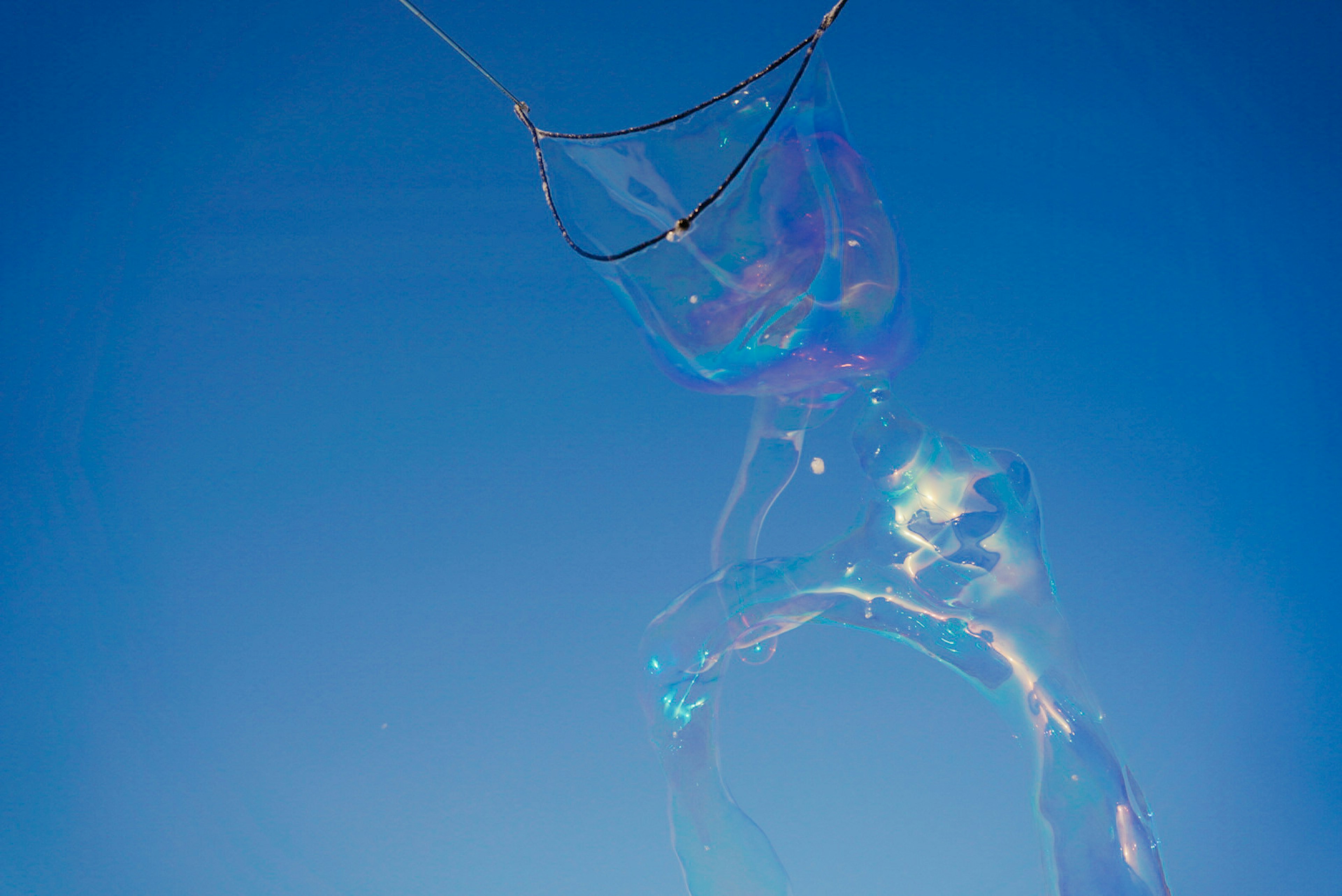 Große Seifenblase schwebt im blauen Himmel mit schillernden Farben