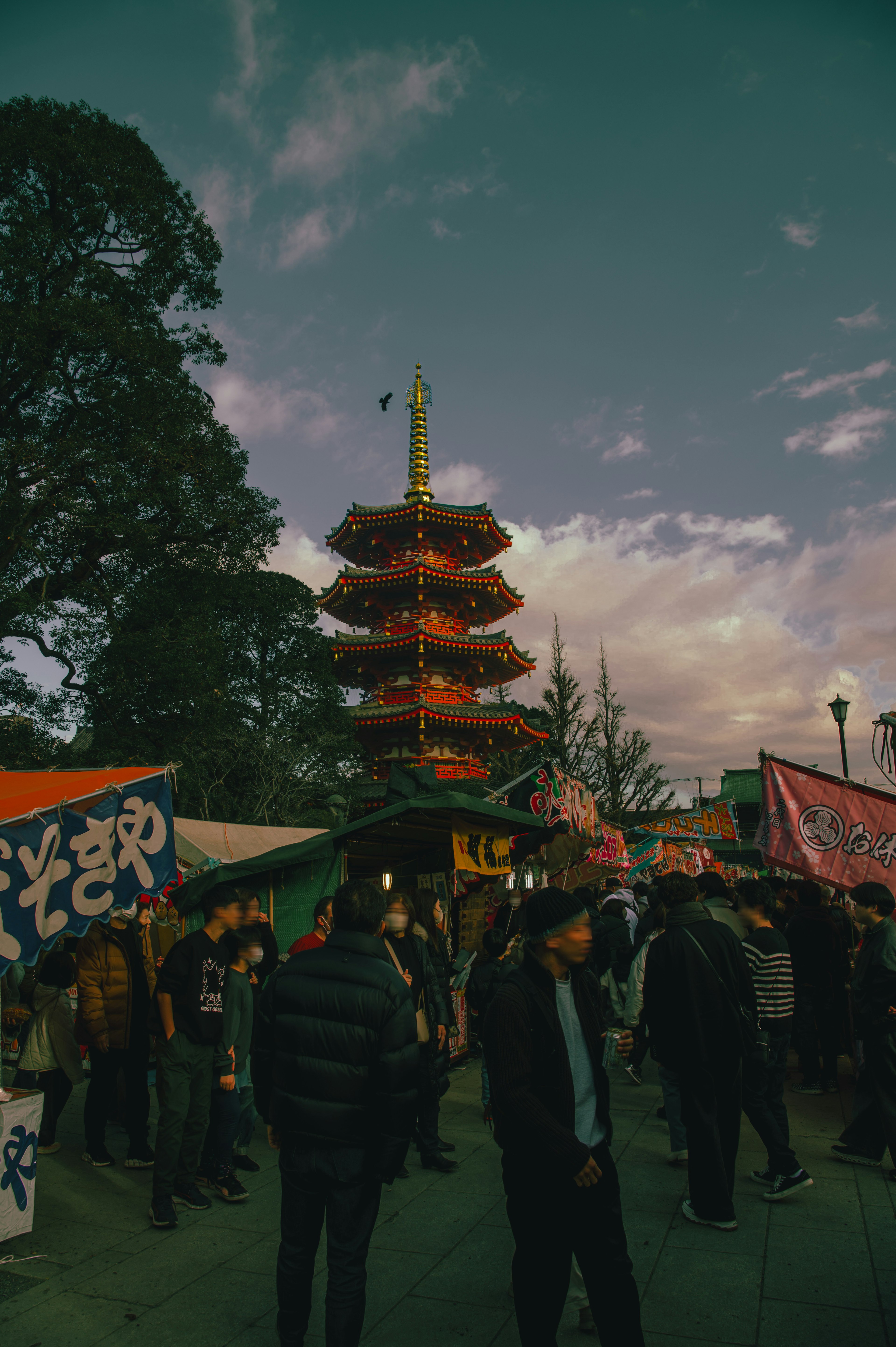 Multitud reunida en un festival con una pagoda al anochecer