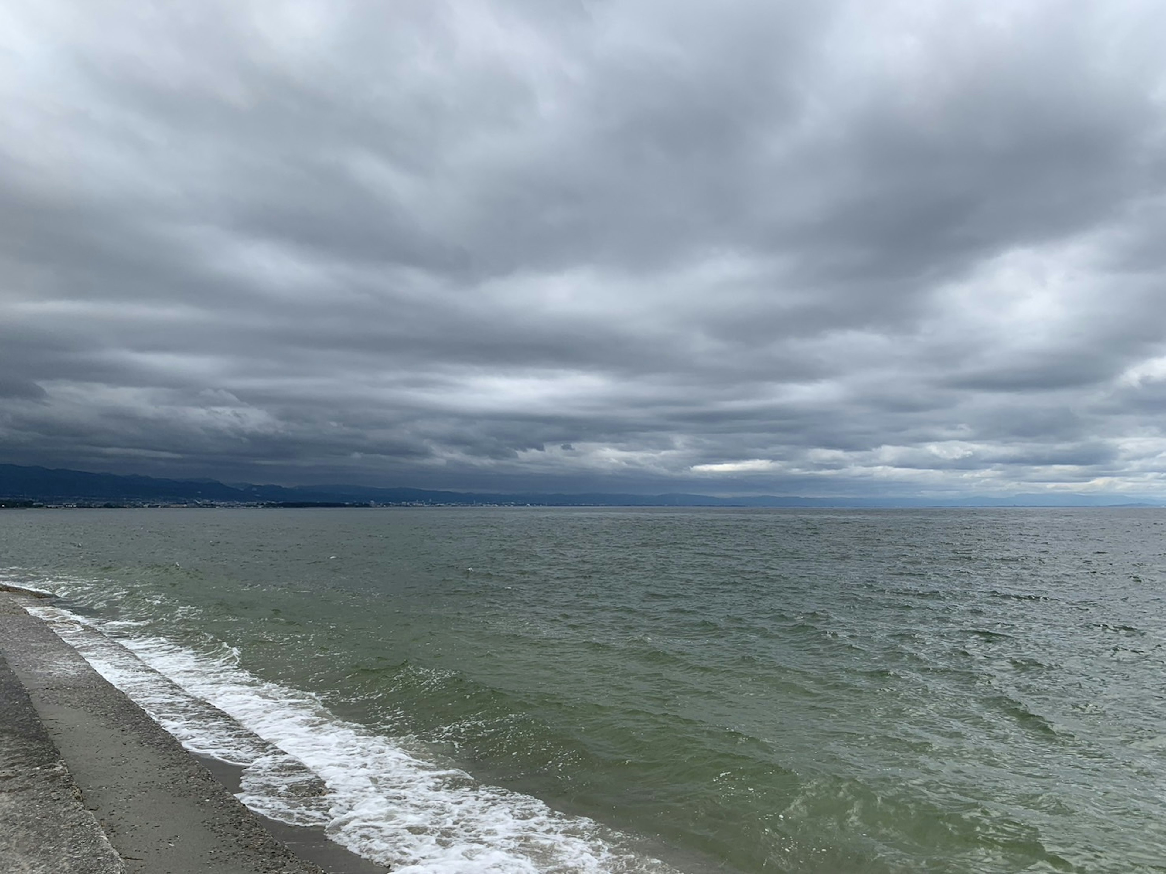 Pemandangan laut dengan langit berawan dan ombak yang menghantam pantai