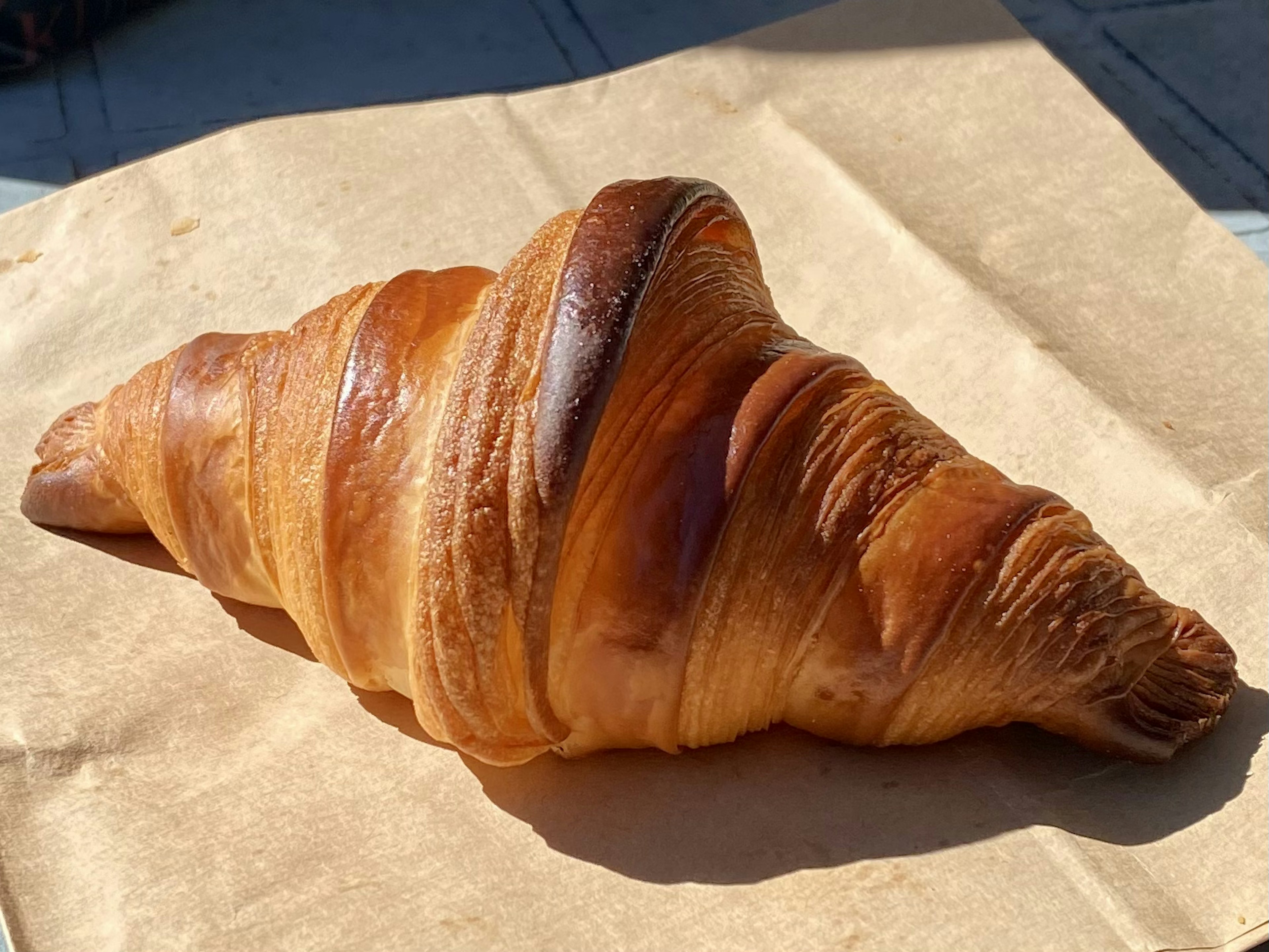 Croissant cokelat keemasan diletakkan di atas kertas cokelat