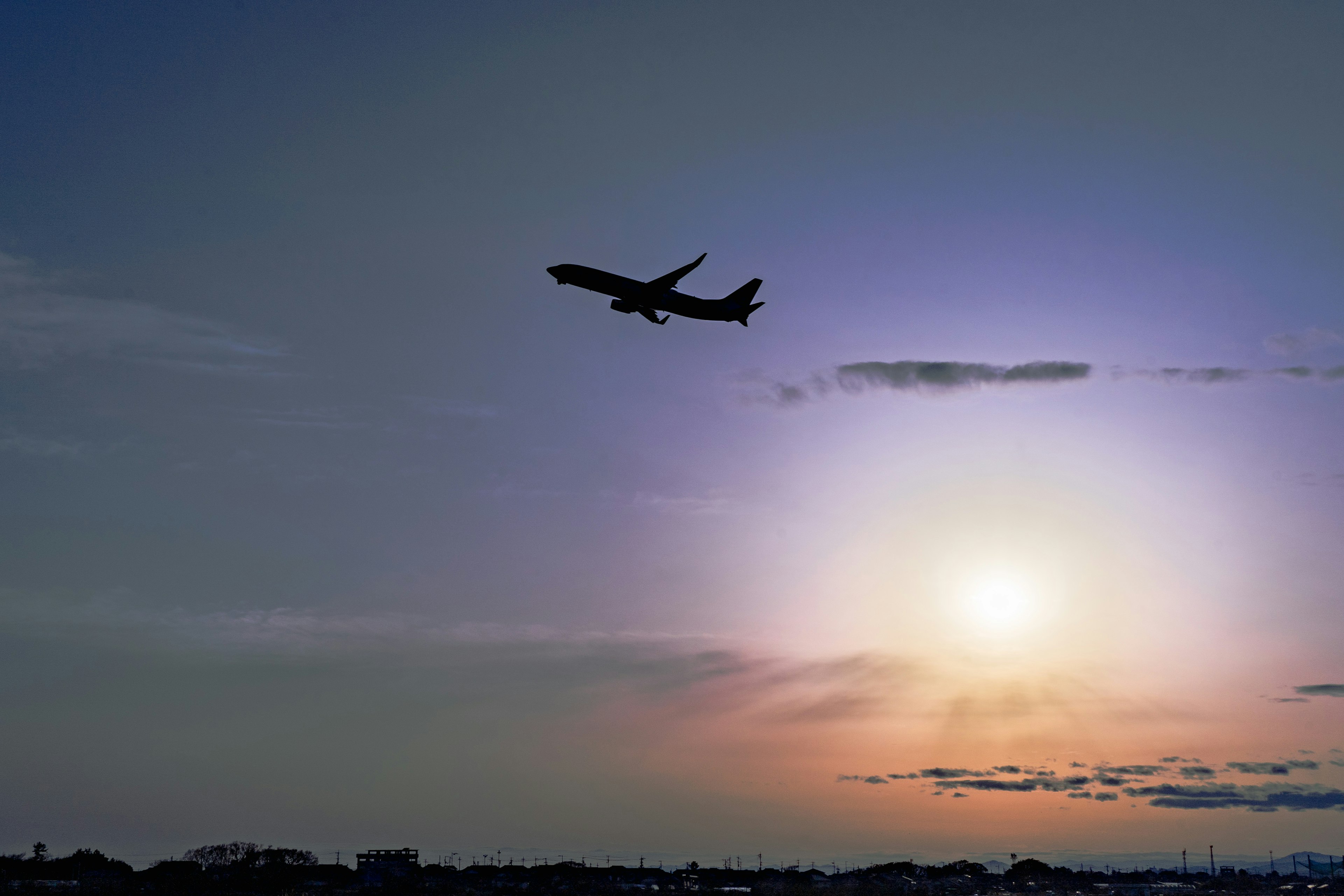 夕焼け空を背景に飛行機が飛び立つ風景