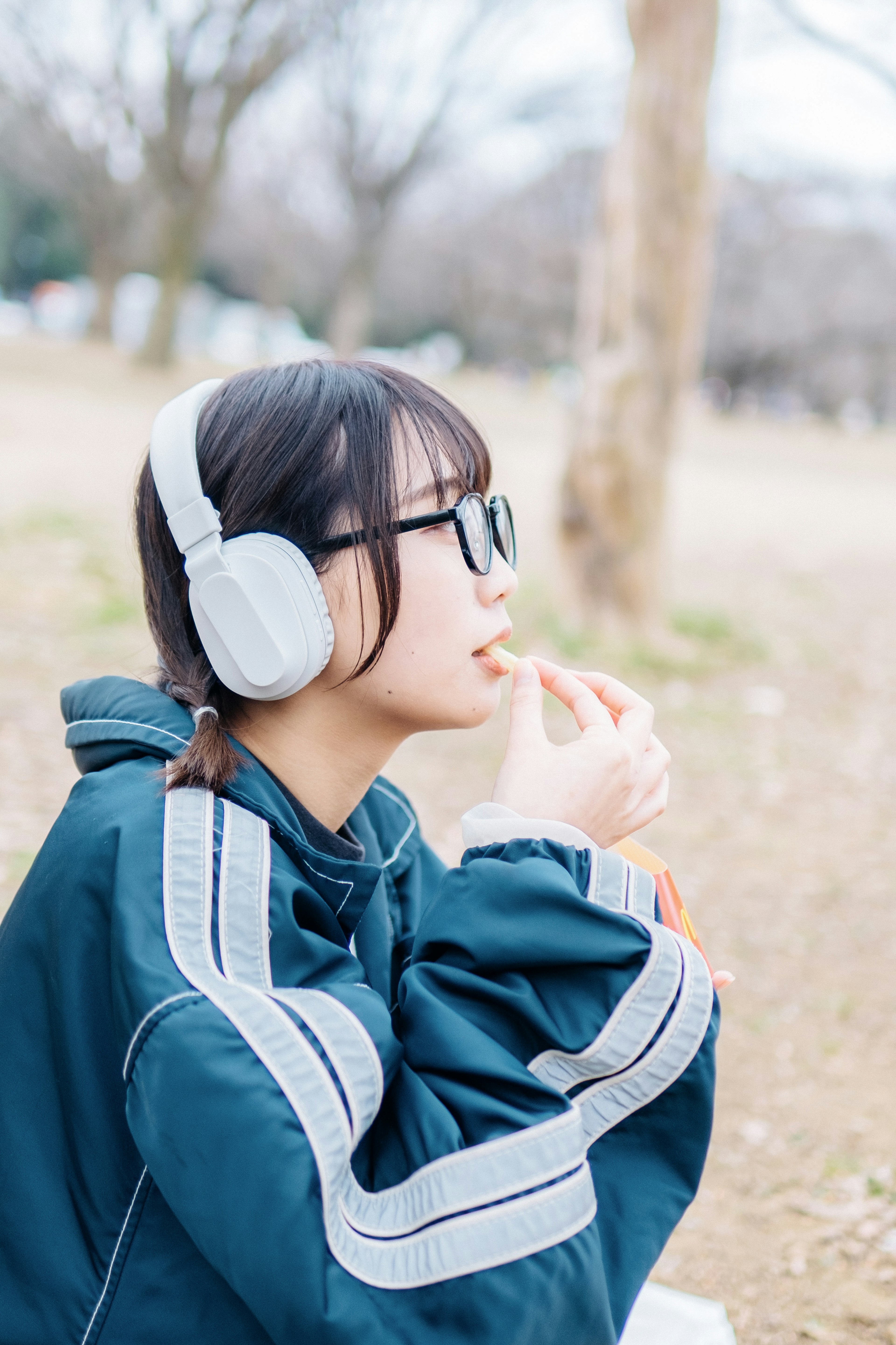 公園でヘッドフォンをつけている女性がスナックを食べているシーン