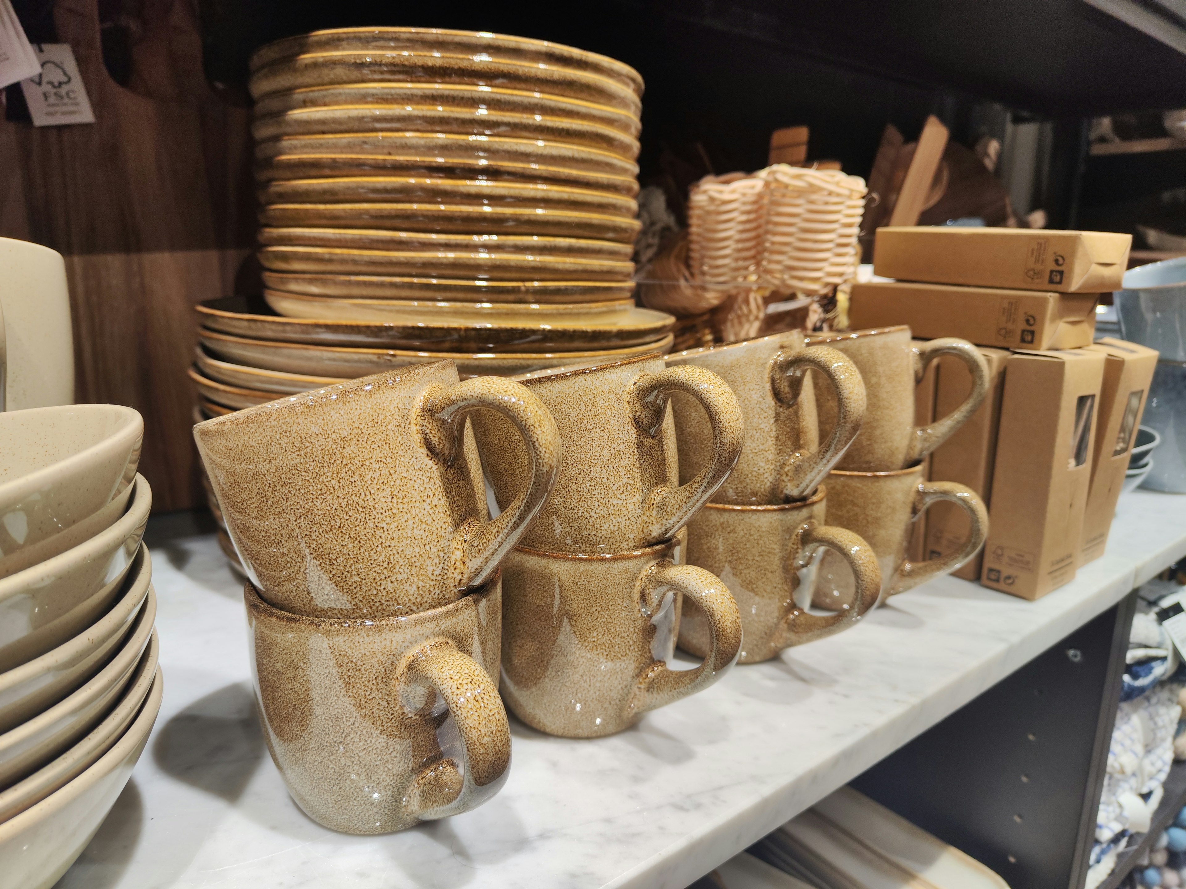 A collection of ceramic cups and plates arranged on a wooden shelf