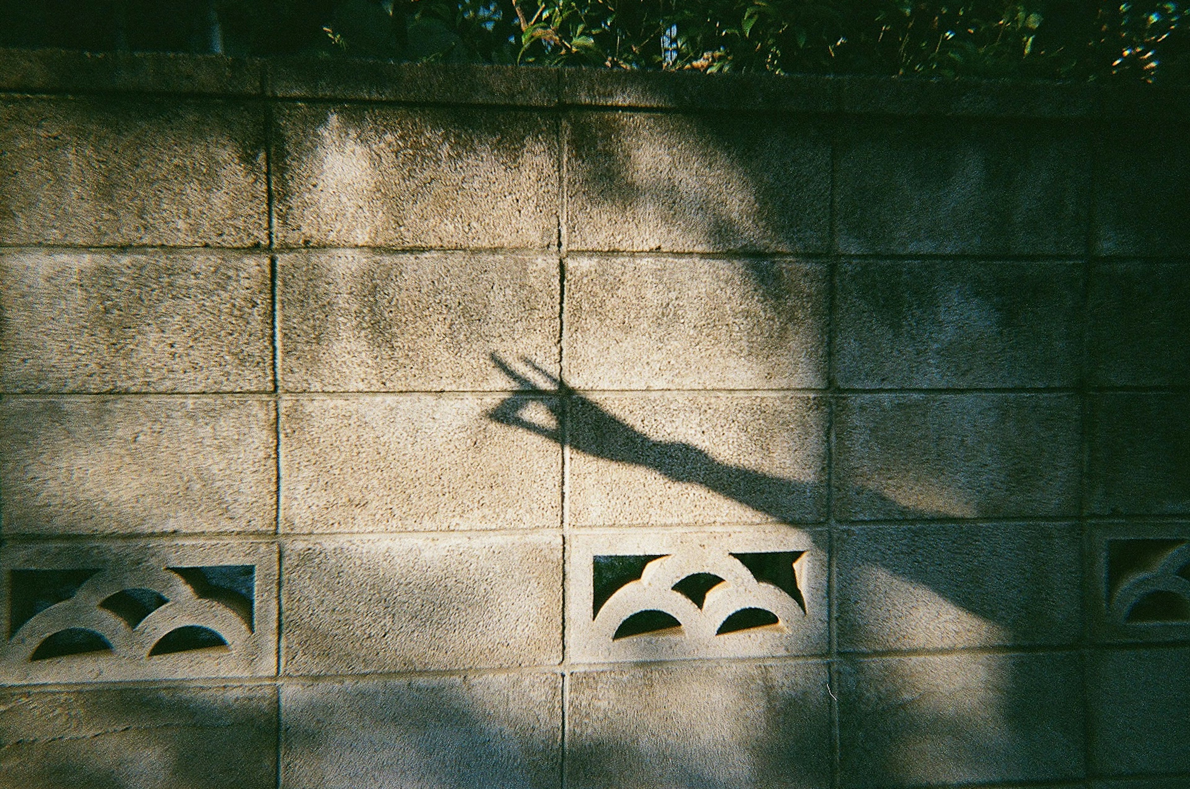 Schatten einer Hand, die ein Friedenszeichen an einer strukturierten Wand macht