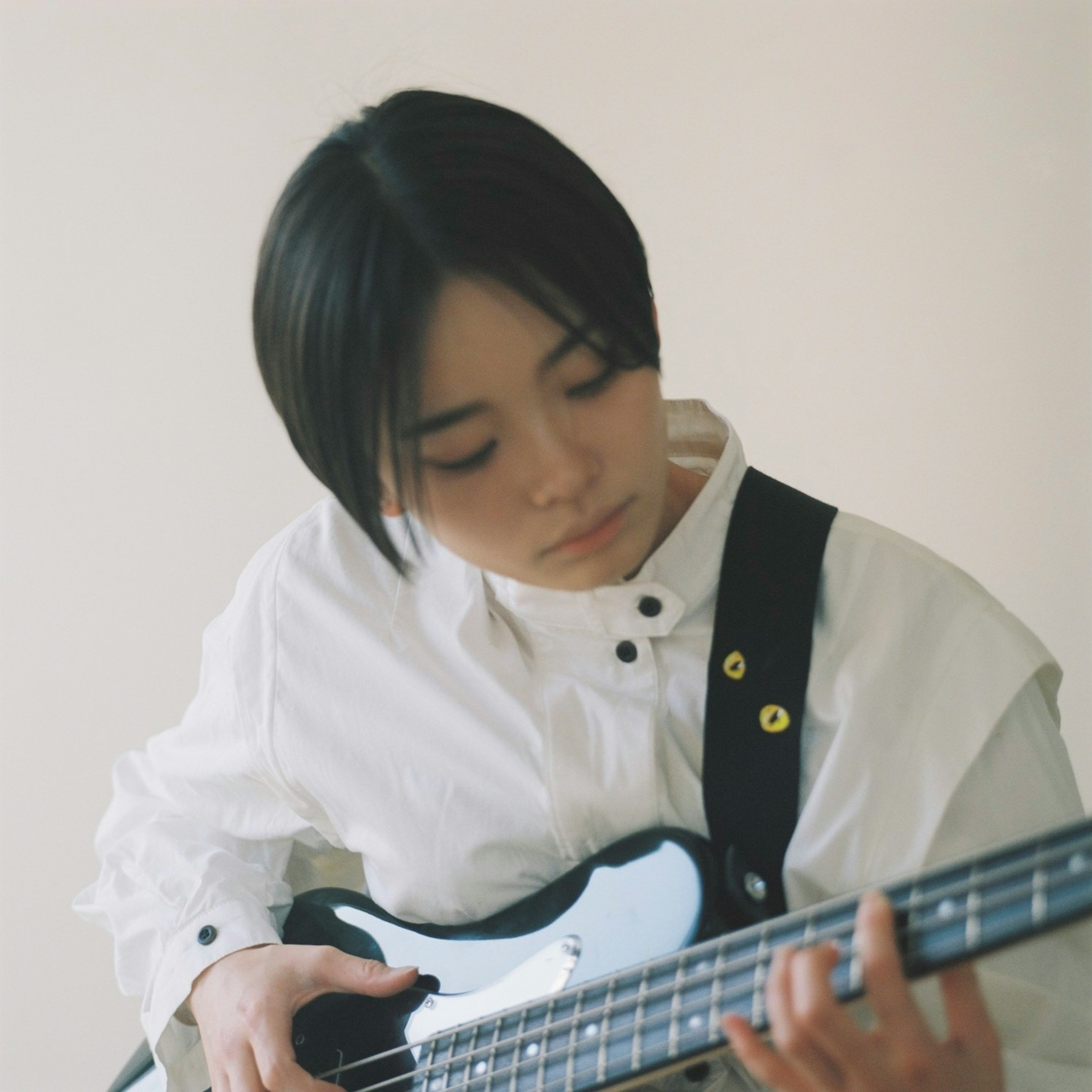 A young woman in a white shirt playing a bass guitar