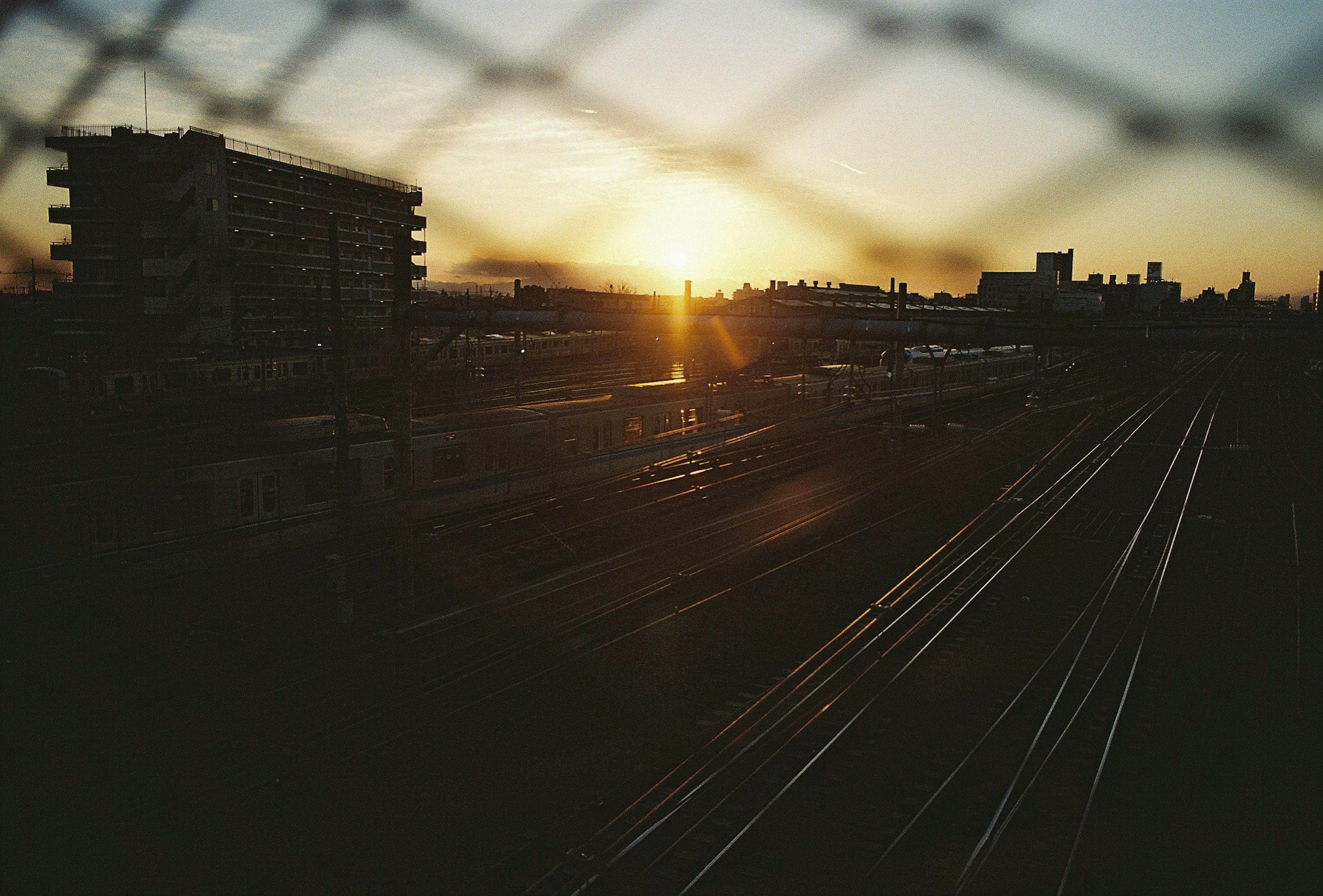 Vista del atardecer con vías de tren y edificios al fondo