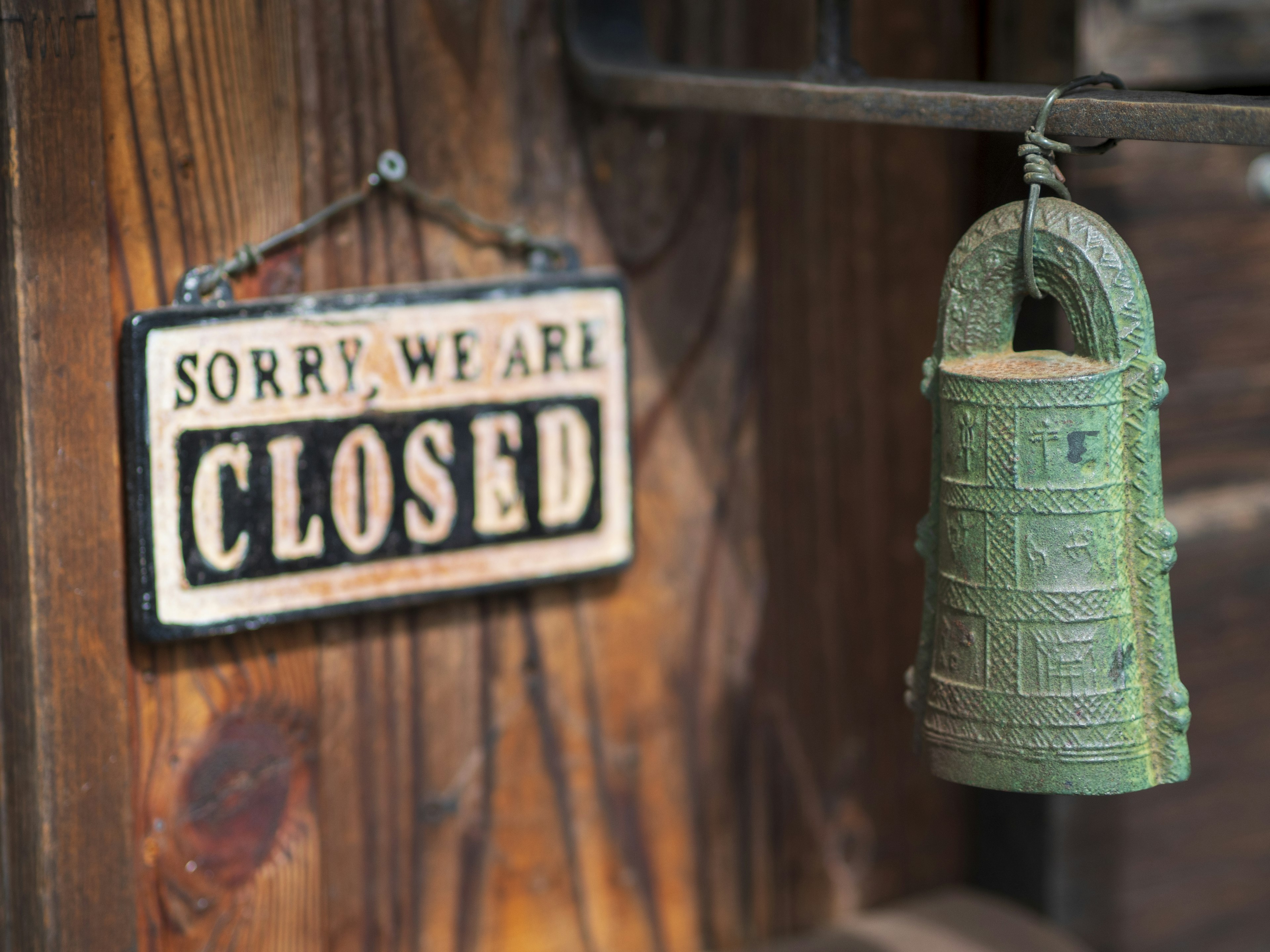 A closed sign alongside a vintage bell hanging on a wooden wall