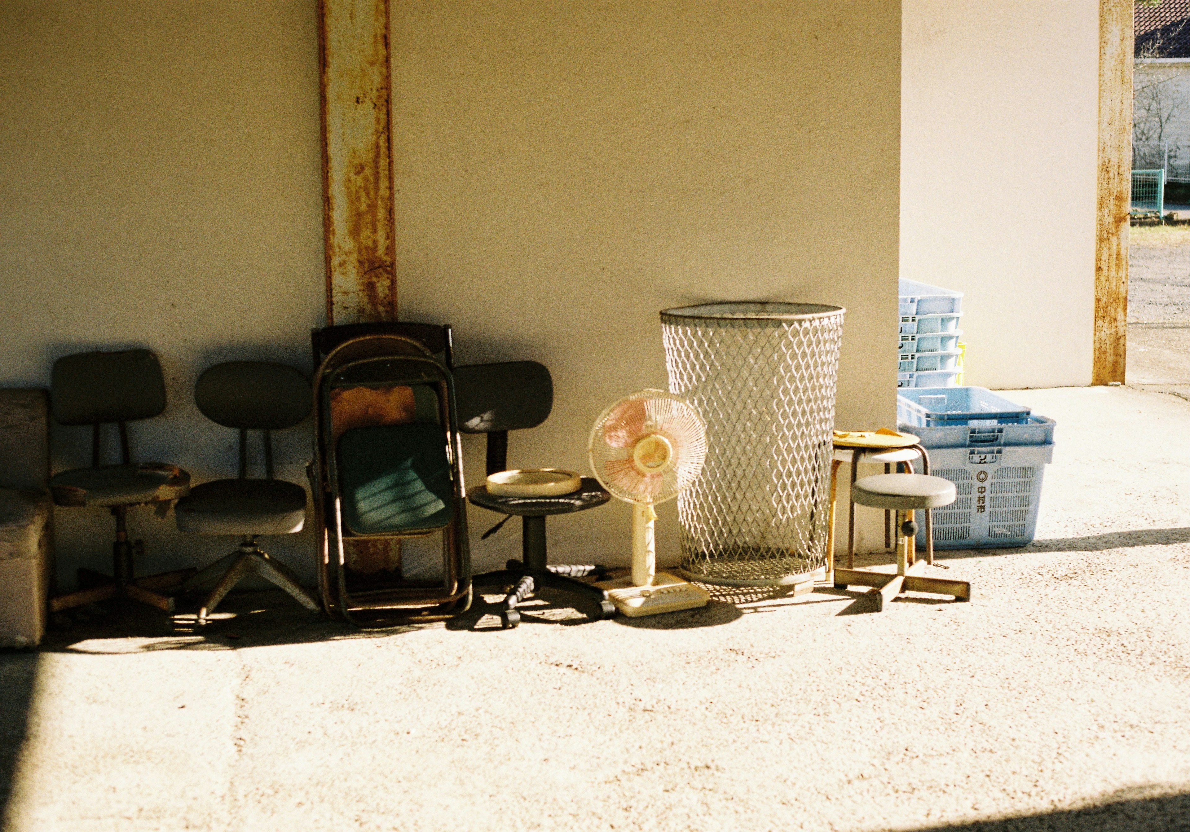 A collection of old chairs and a fan arranged outdoors