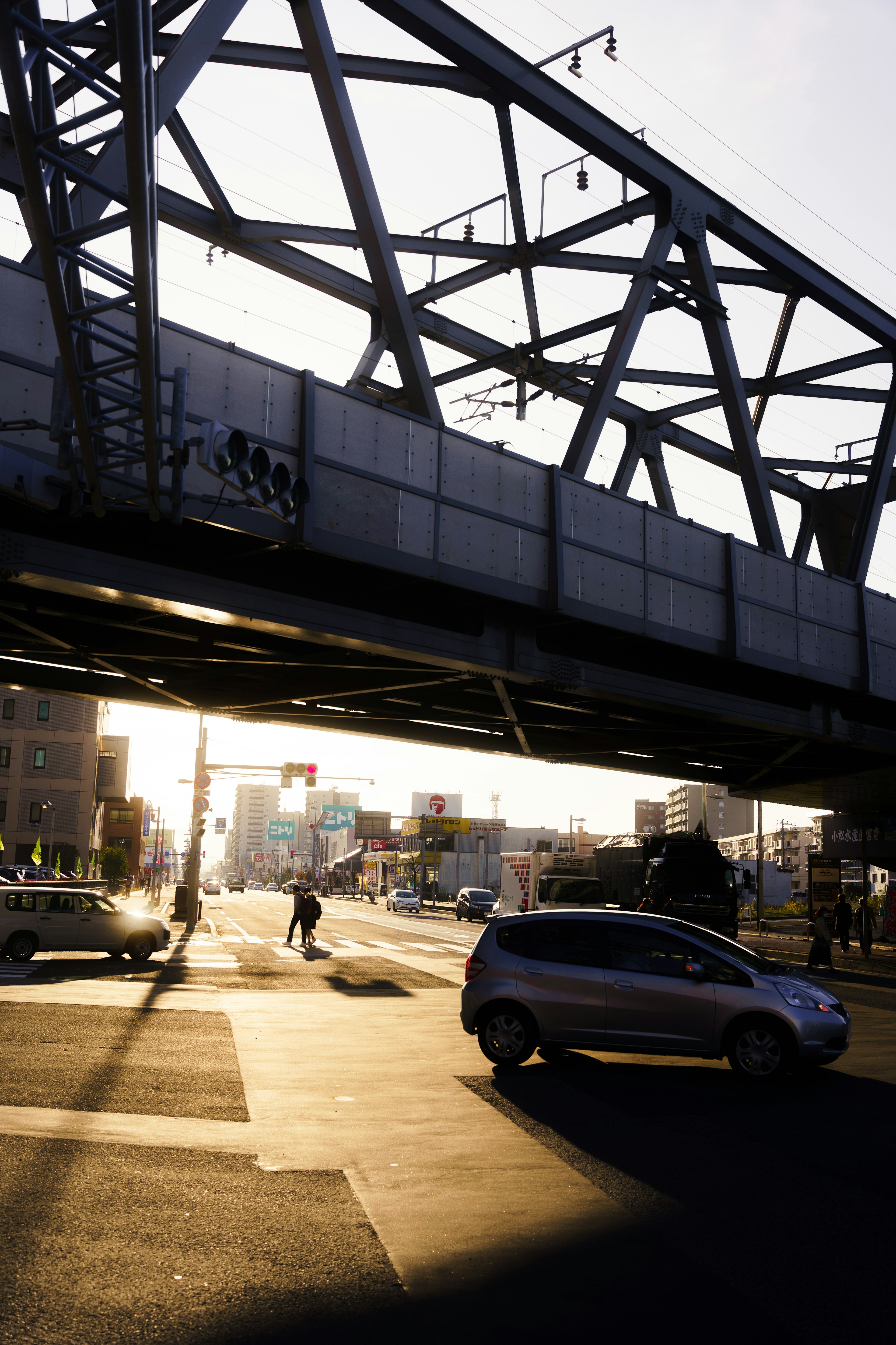 Une silhouette d'un pont ferroviaire au coucher du soleil avec des voitures traversant l'intersection