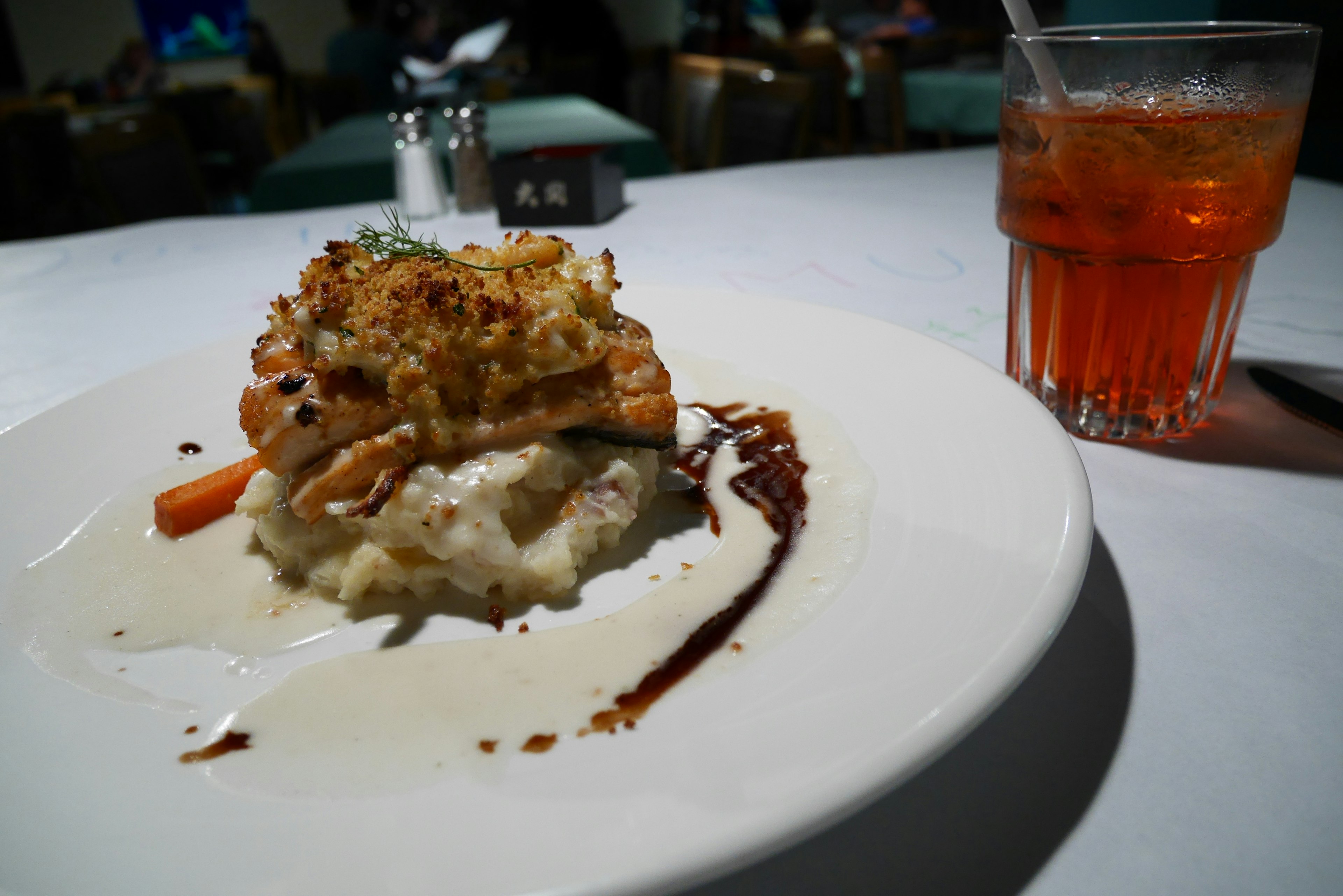 Assiette de risotto crémeux surmontée de poulet grillé et de légumes avec une boisson orange vif