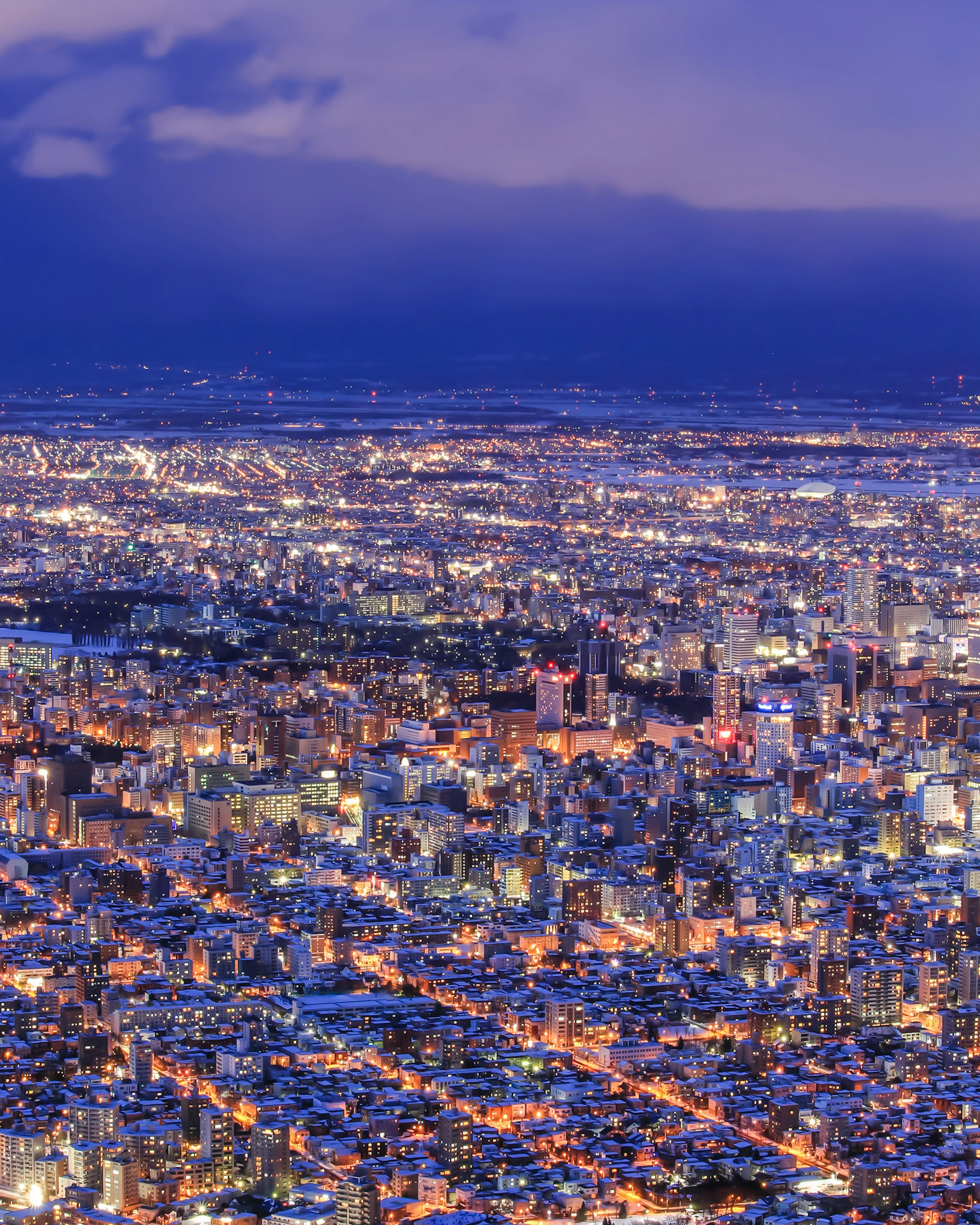 Luftaufnahme einer Stadt bei Nacht mit Wolkenkratzern und Stadtlichtern