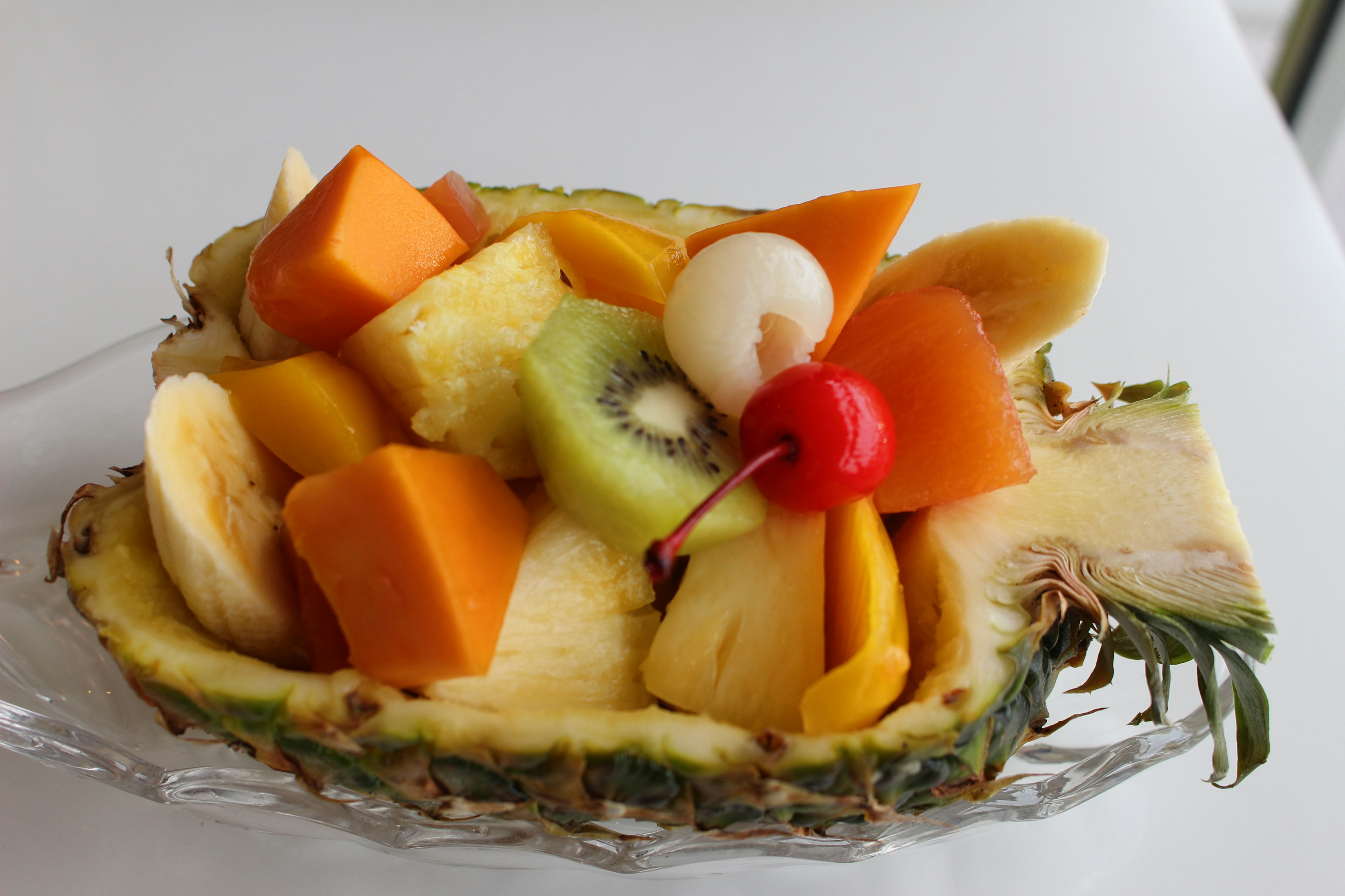 Salade de fruits servie dans un bateau d'ananas avec divers fruits colorés