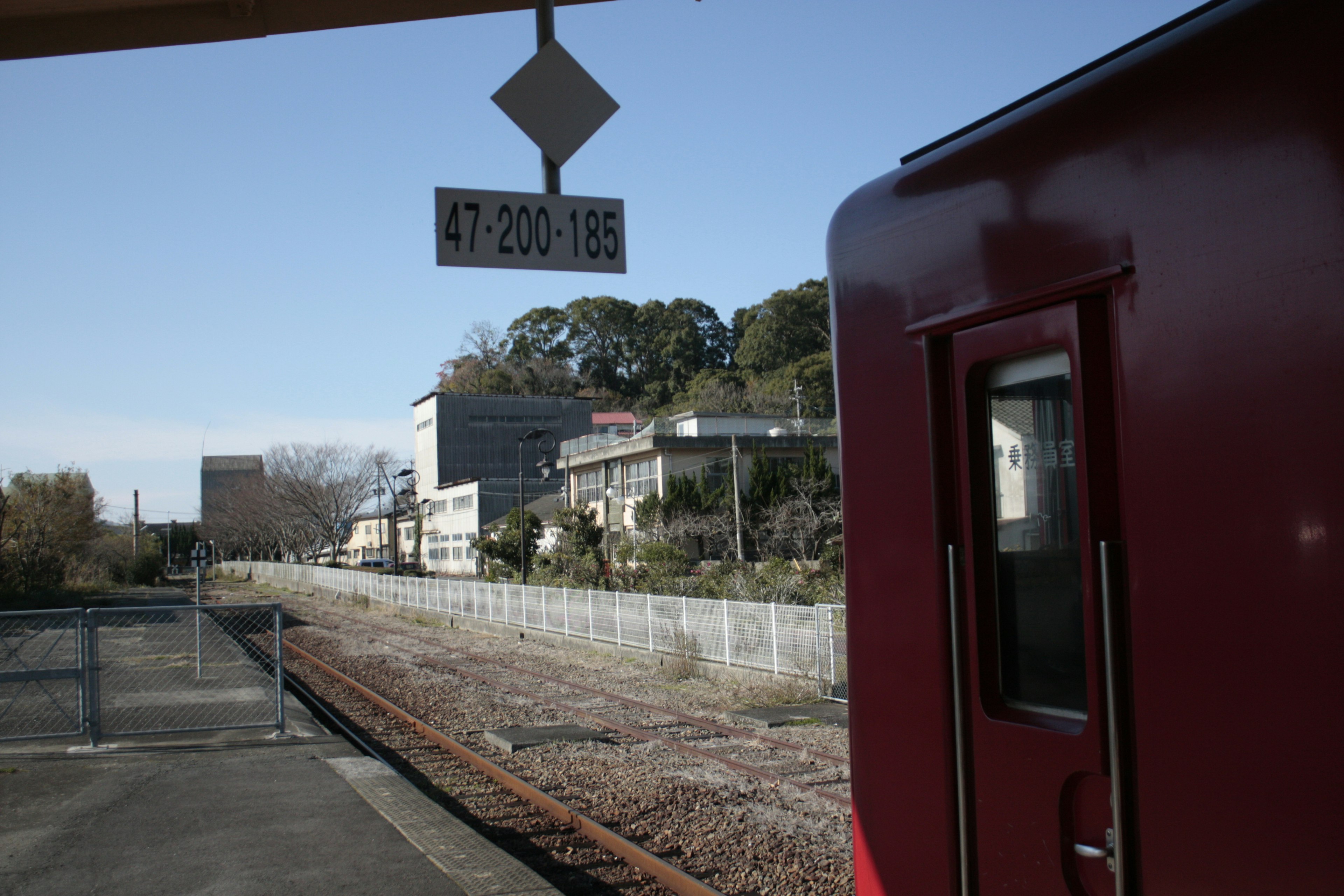 赤い電車が停車している駅の風景 住宅街が背景に見える