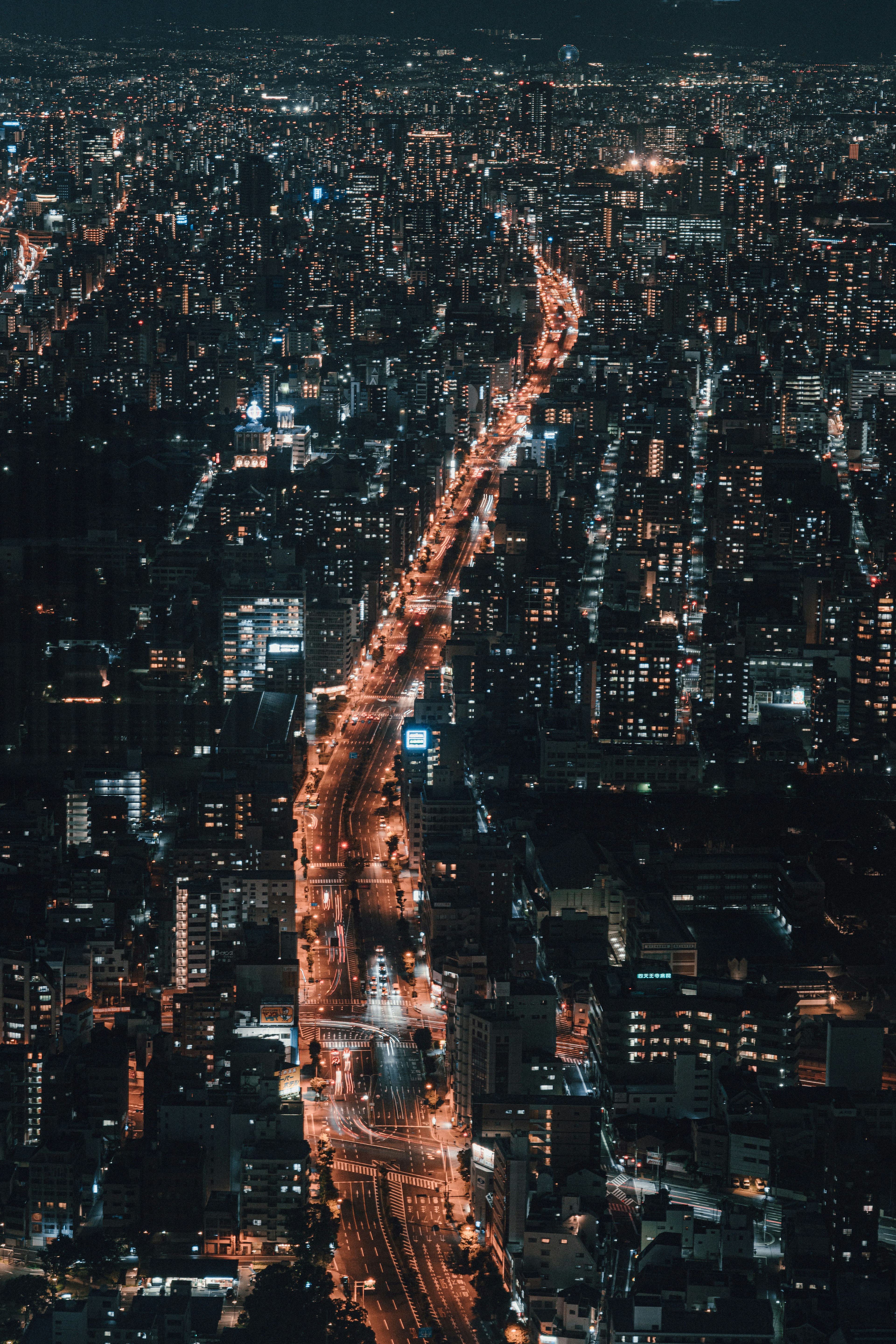 Aerial view of a city skyline at night with a winding road illuminated by streetlights