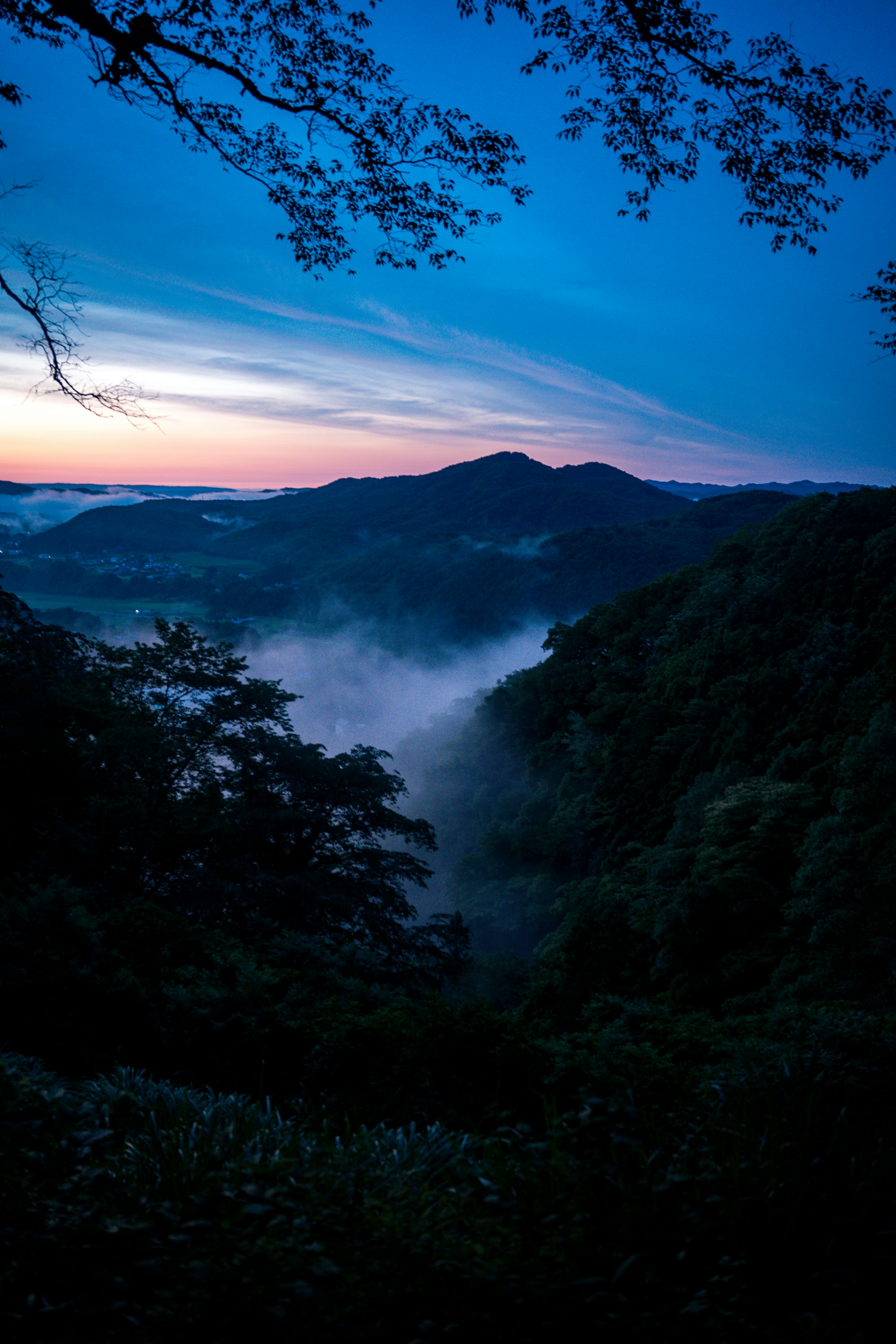 青い夕暮れの山々と霧の谷