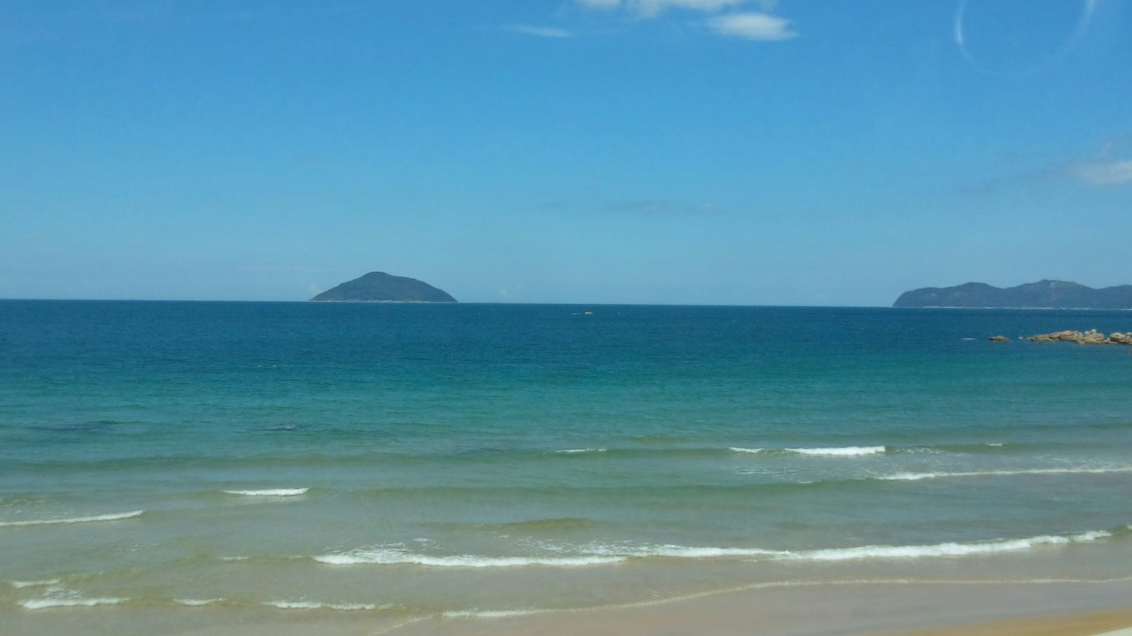 Scenic view of blue ocean and sky with distant island