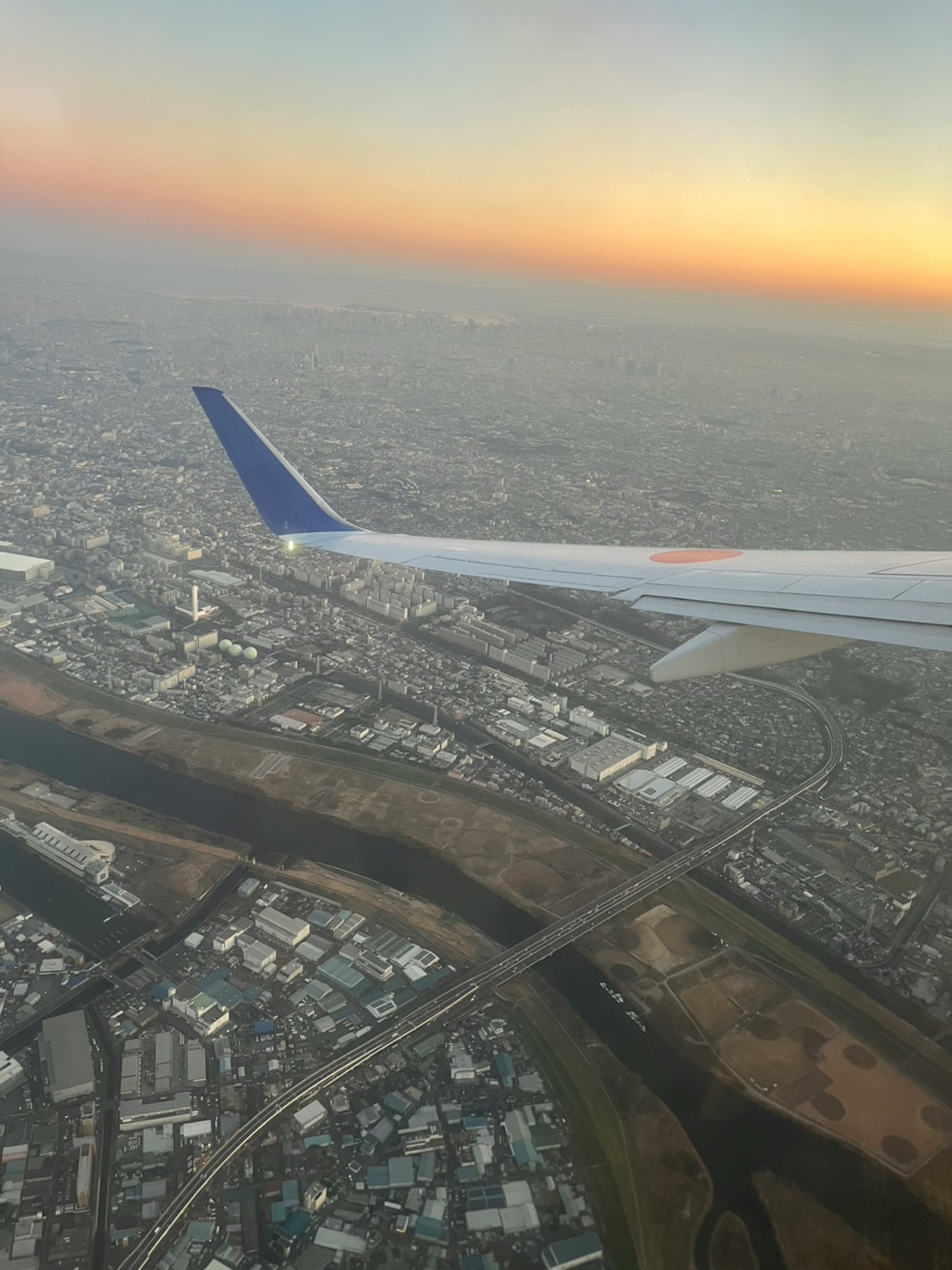 航空機の翼と都市の景色が広がる夕暮れの空