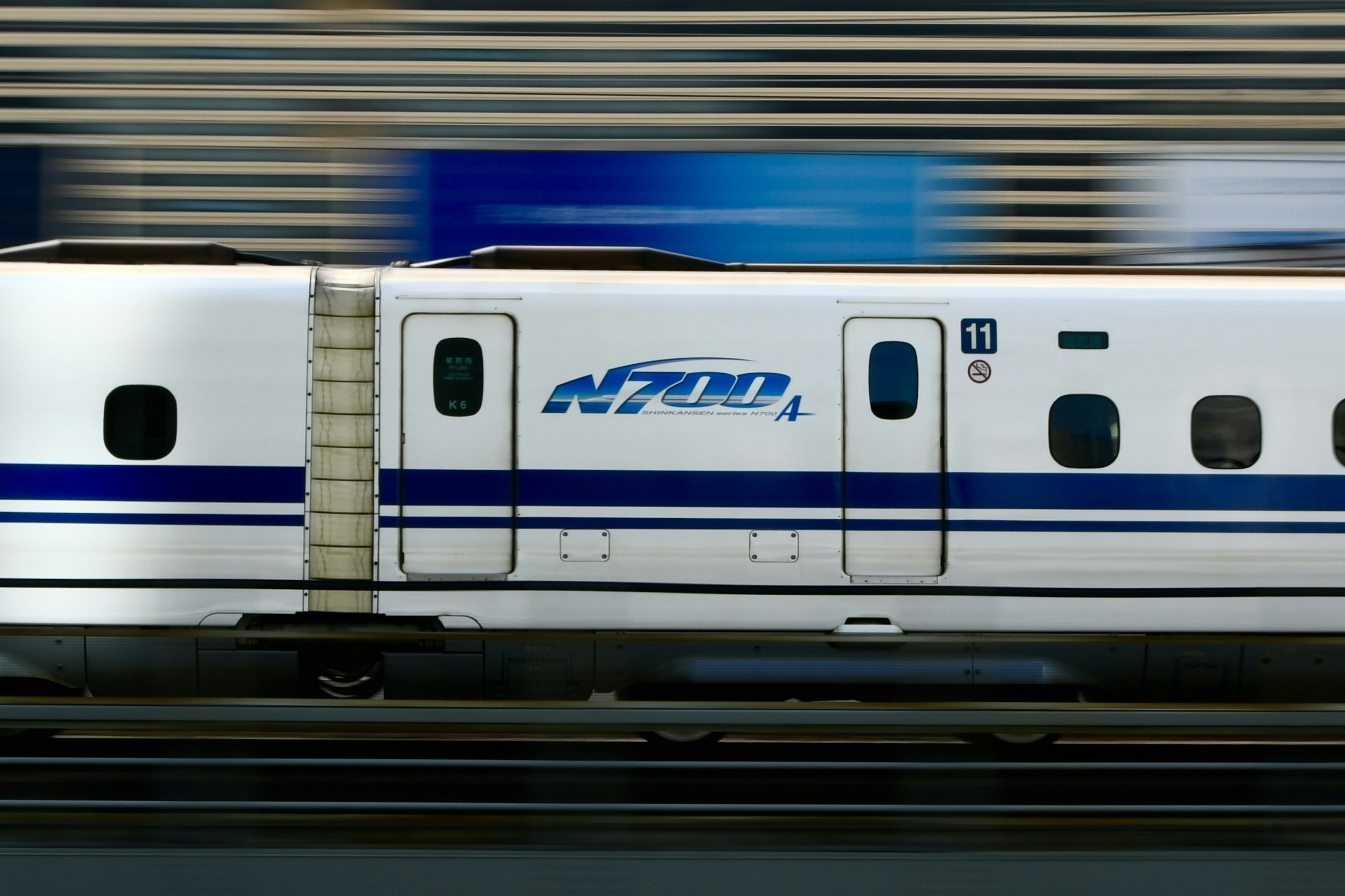 Shinkansen train speeding by with blue and white design