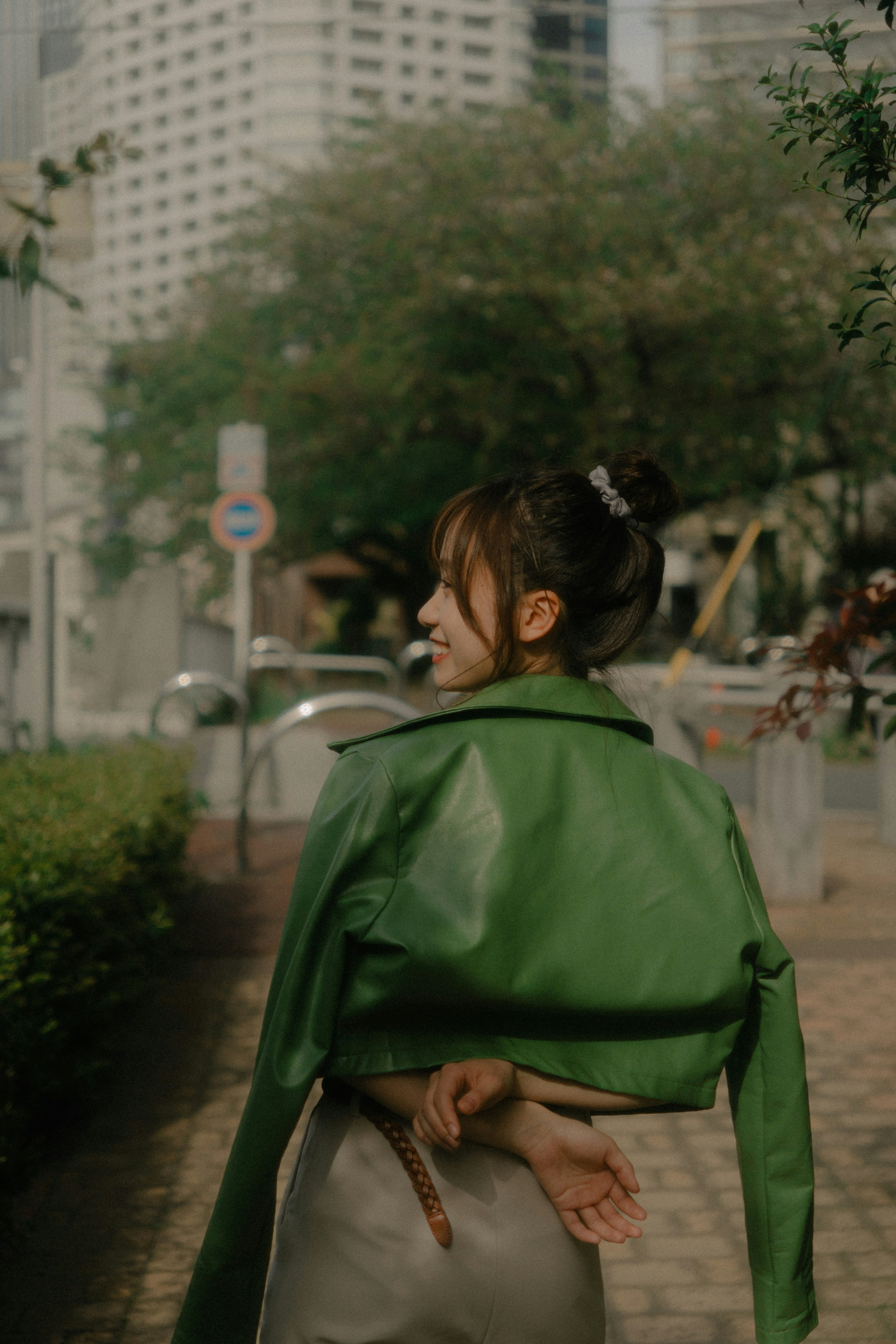 Une femme portant une veste verte de dos dans un cadre urbain