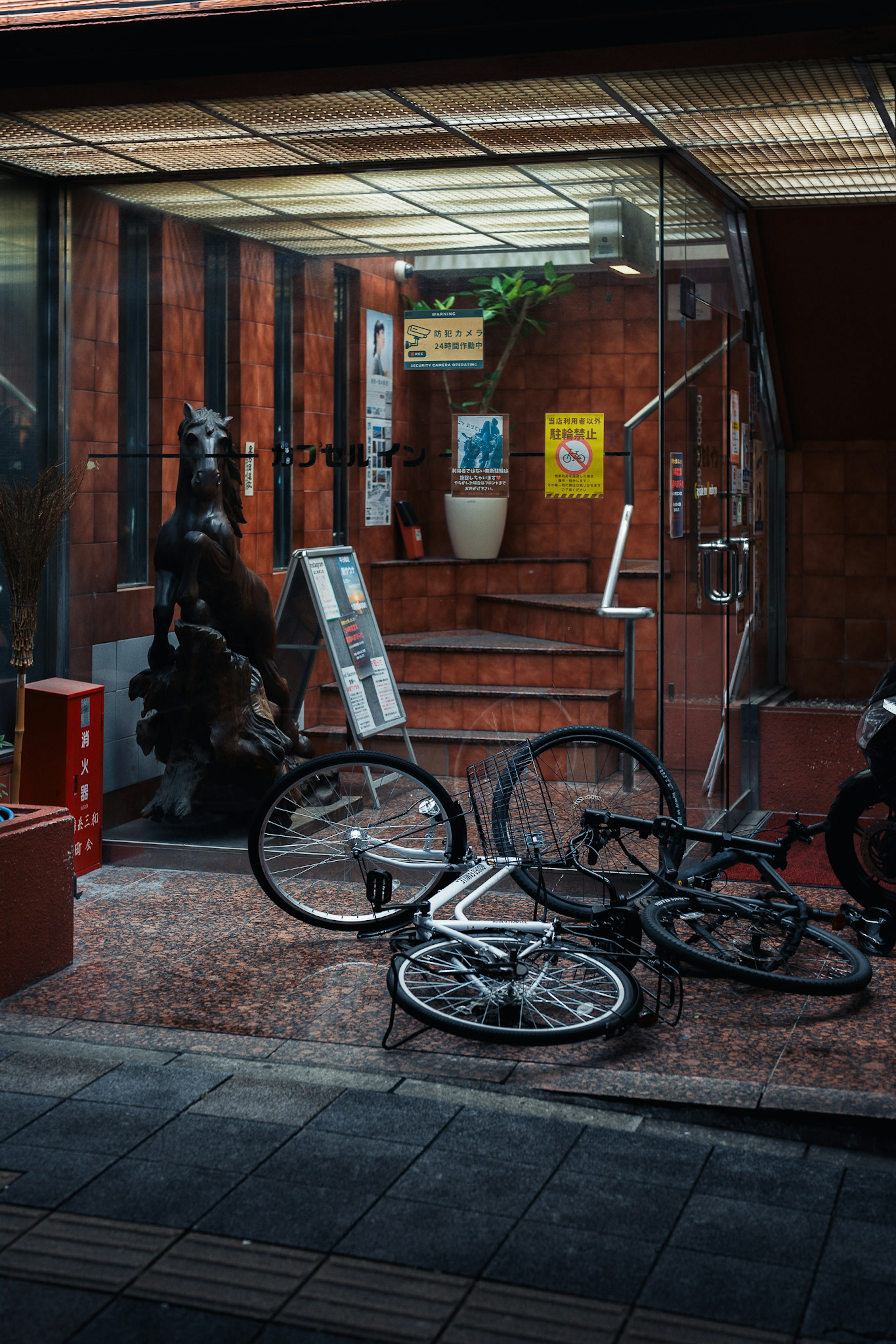 Scène urbaine avec des bicyclettes tombées et une statue près des escaliers