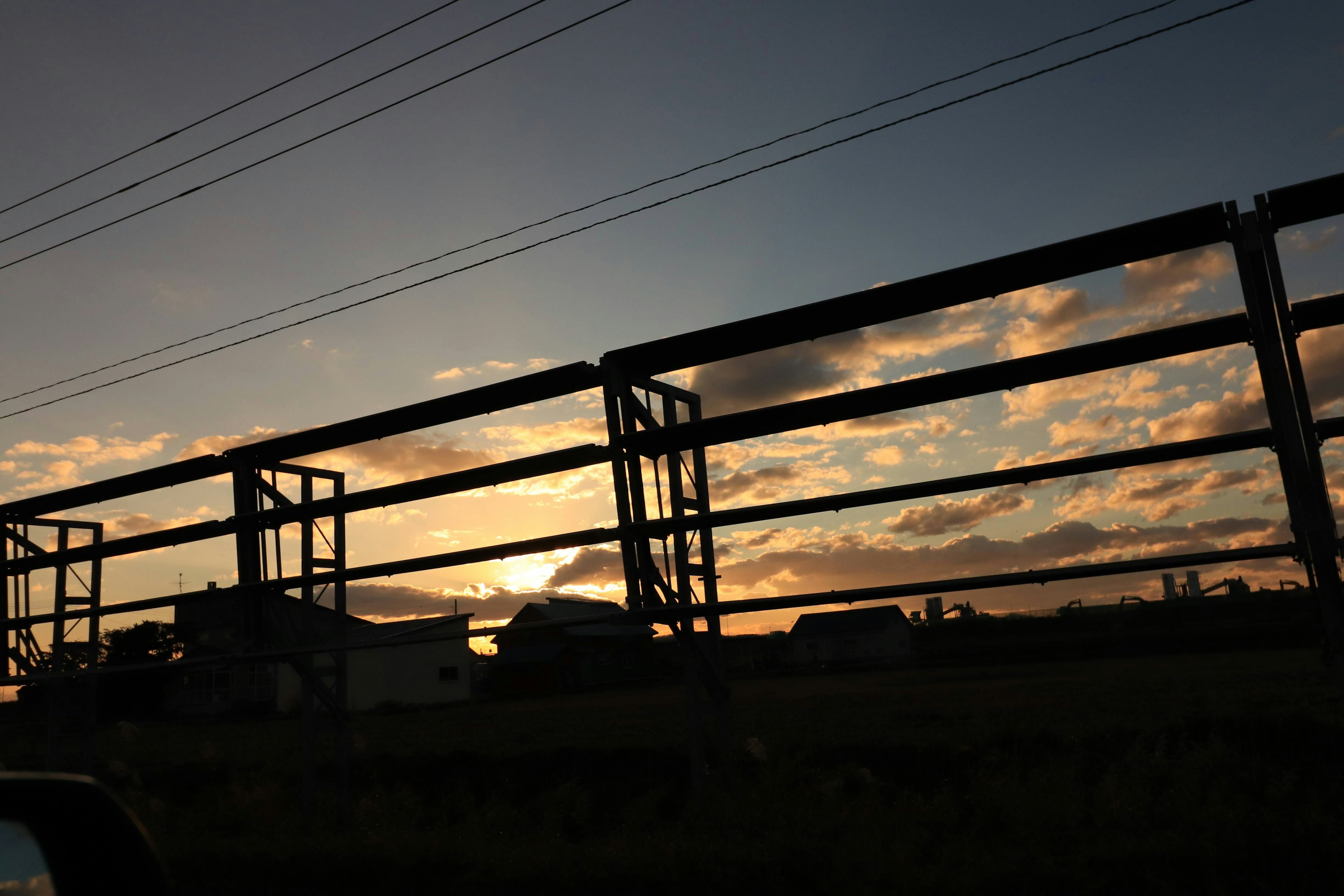 夕日が雲の間から見える風景と鉄のフェンス