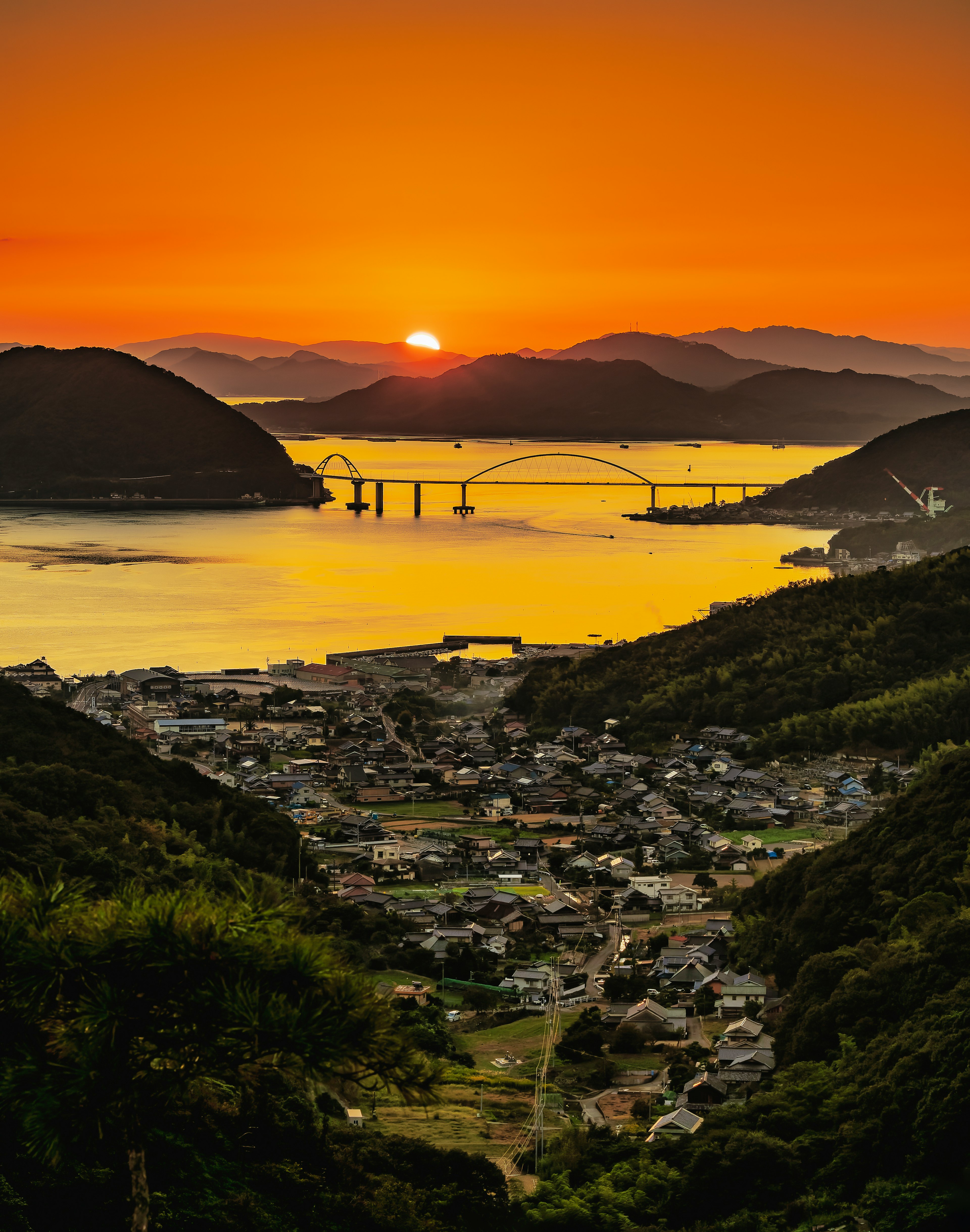 美しい夕日が山々と海に反射する風景 町と橋が見える