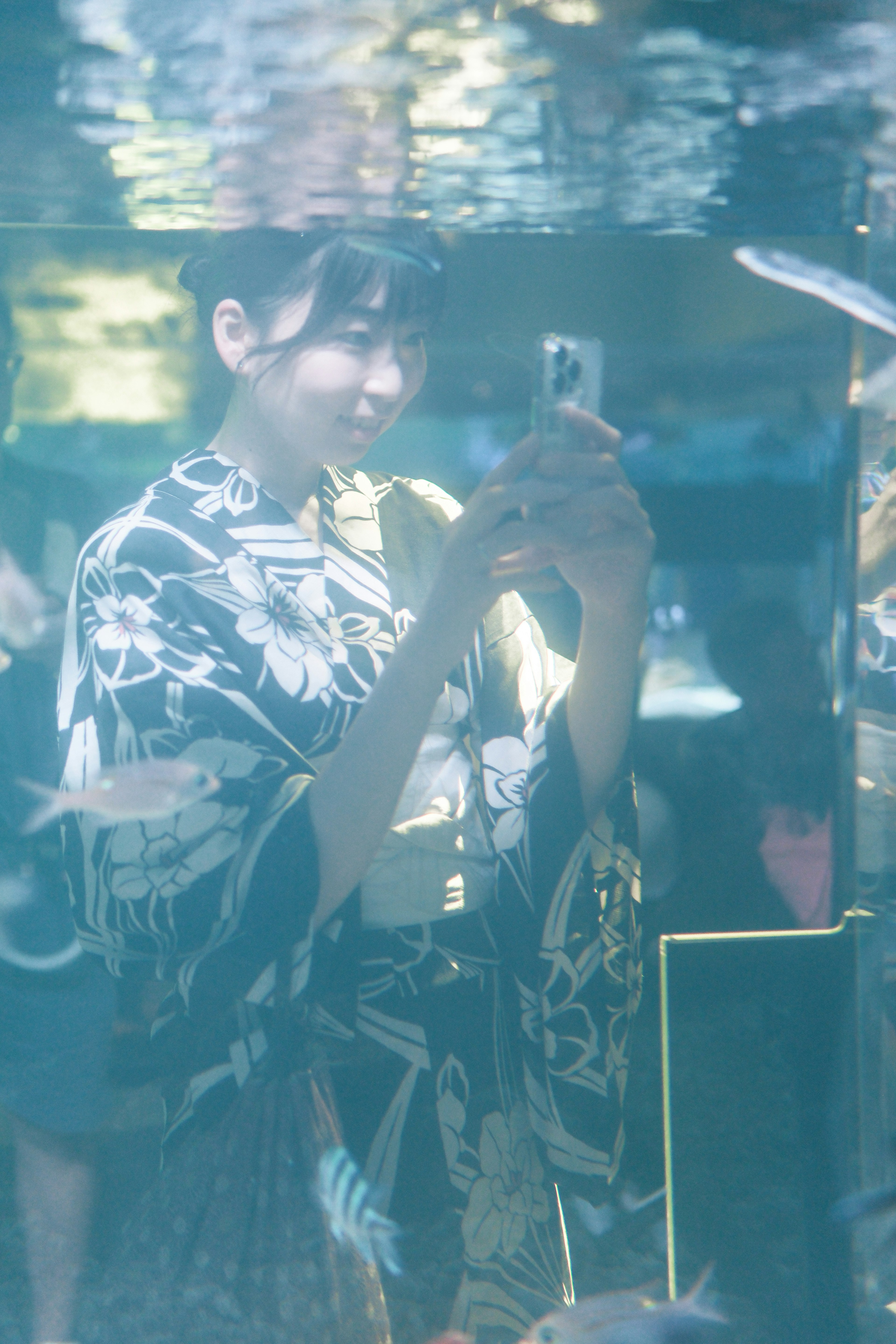 Mujer en kimono tomando un selfie bajo el agua con peces nadando alrededor