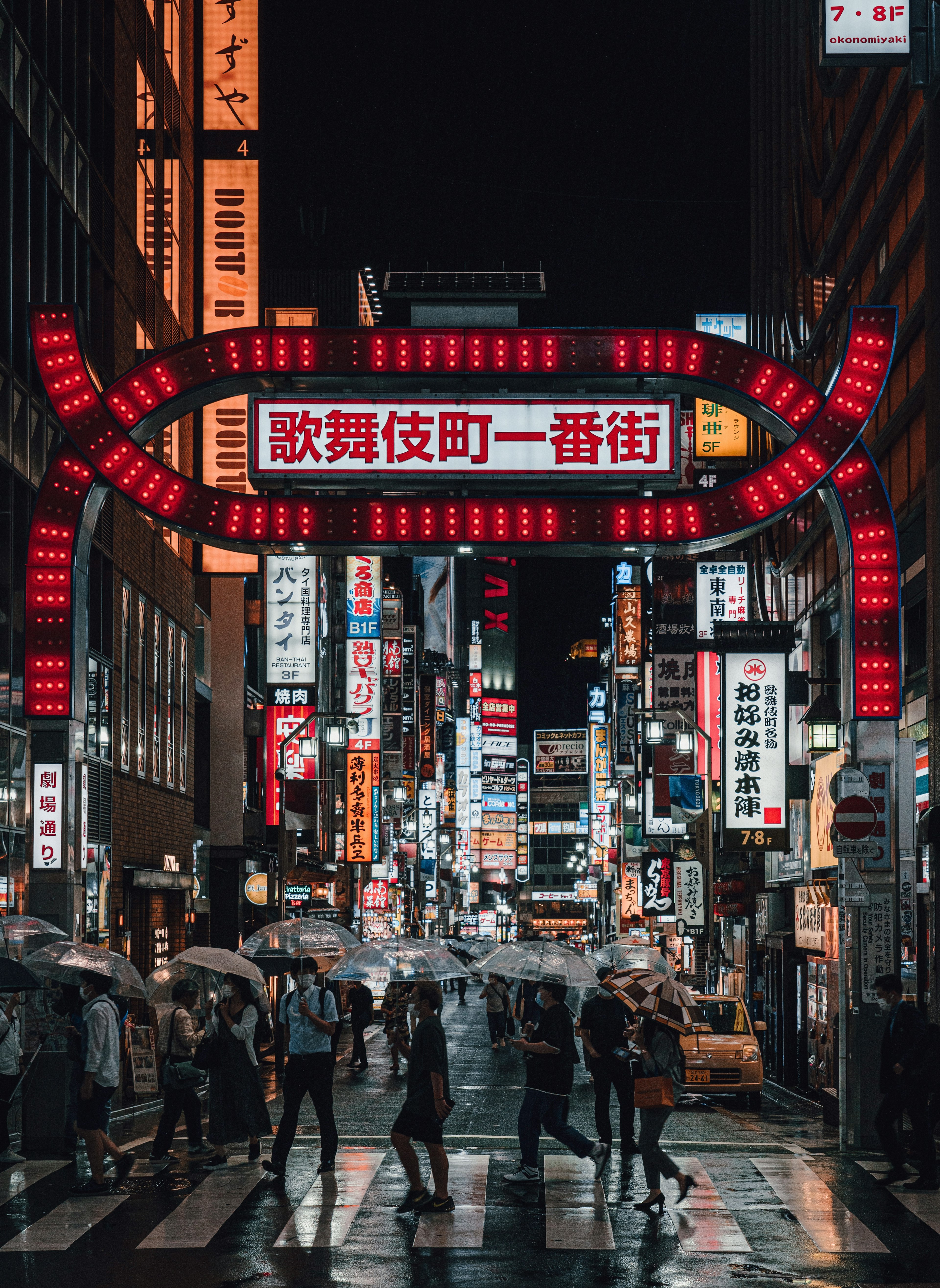 夜の街に立つ赤い看板と人々が交差する風景