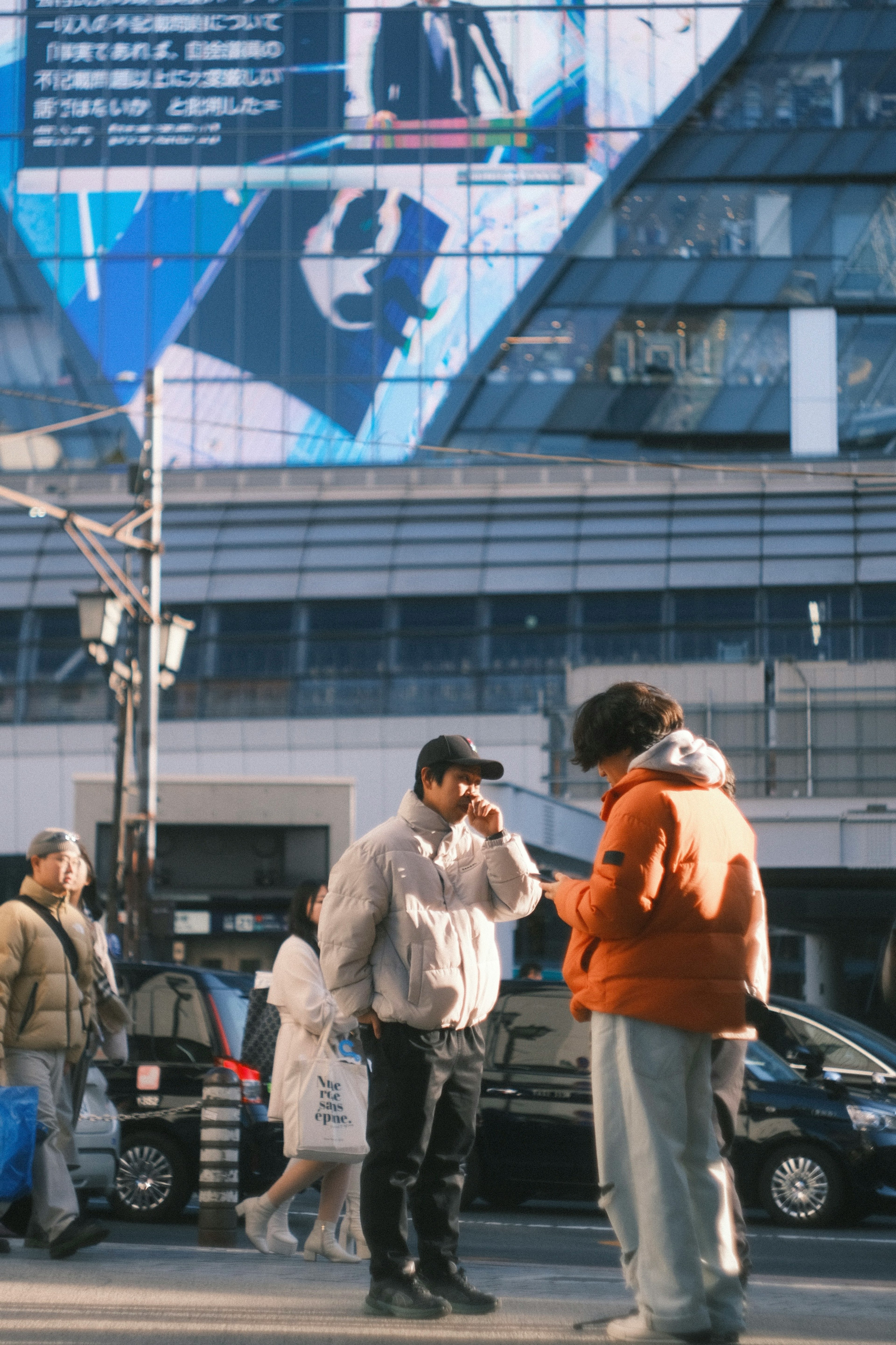 Two men conversing at an urban intersection with a large billboard in the background