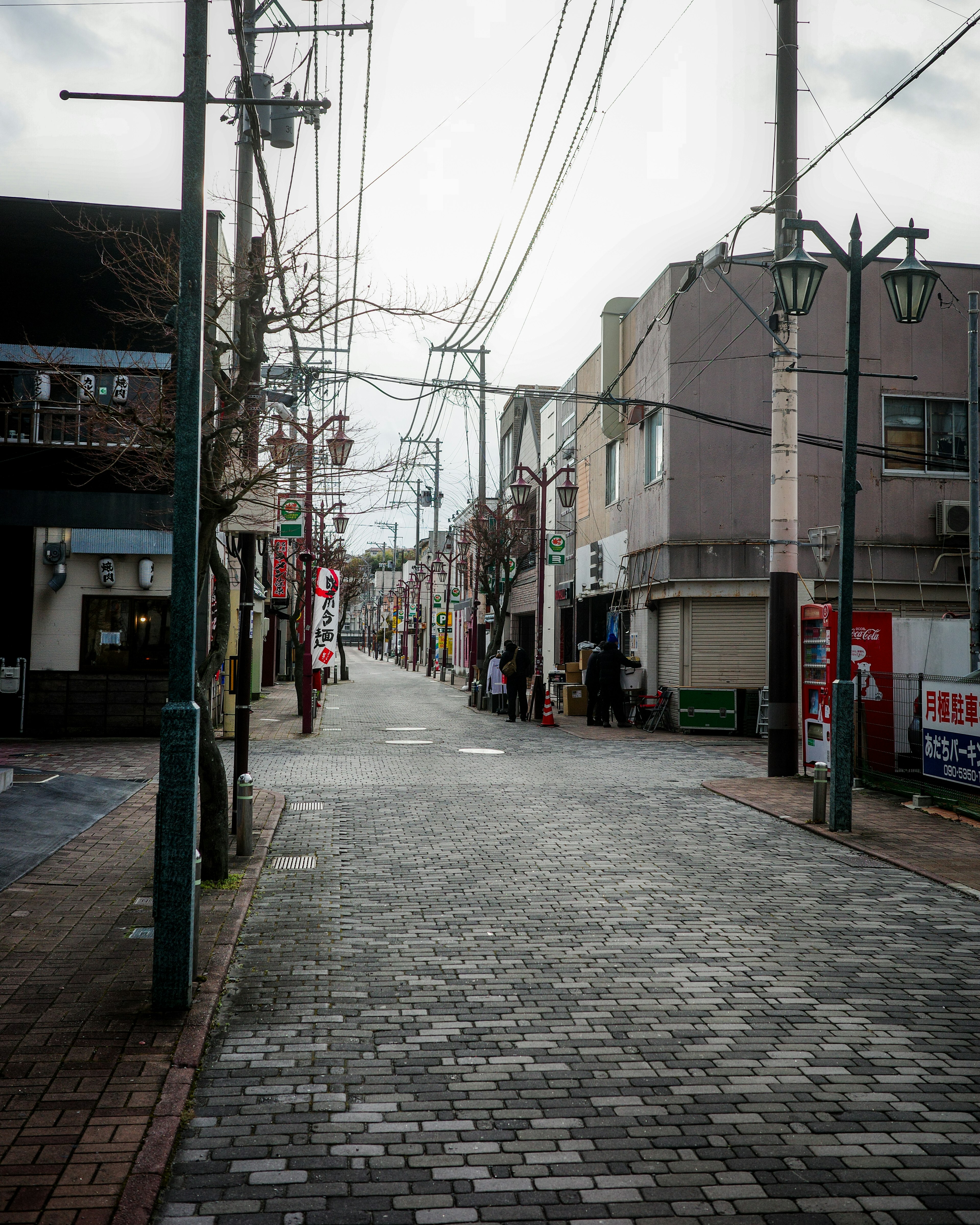 静かな街並みの石畳の通りに沿った店舗と電柱