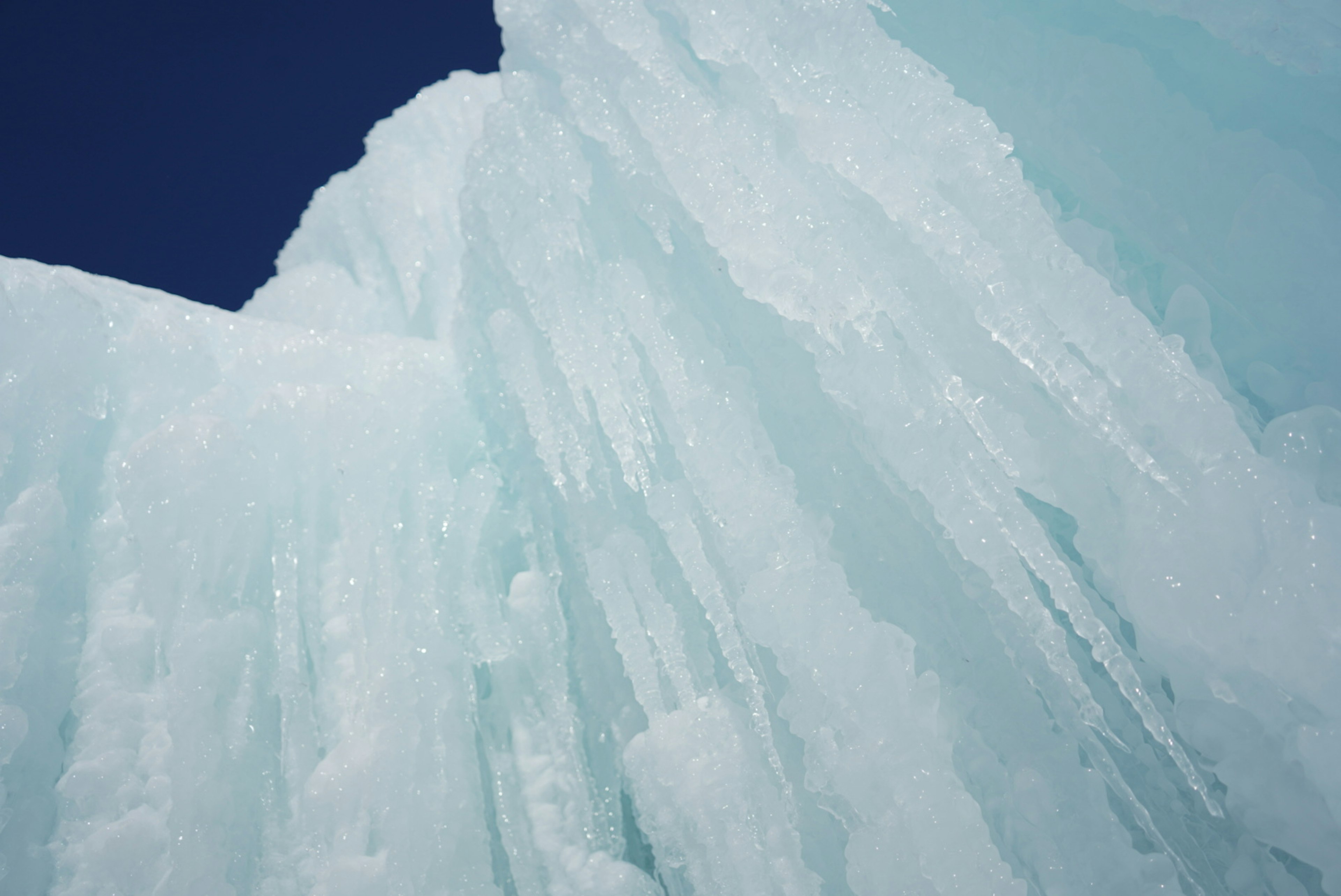 Primer plano de una gran pared de hielo con cielo azul brillante de fondo