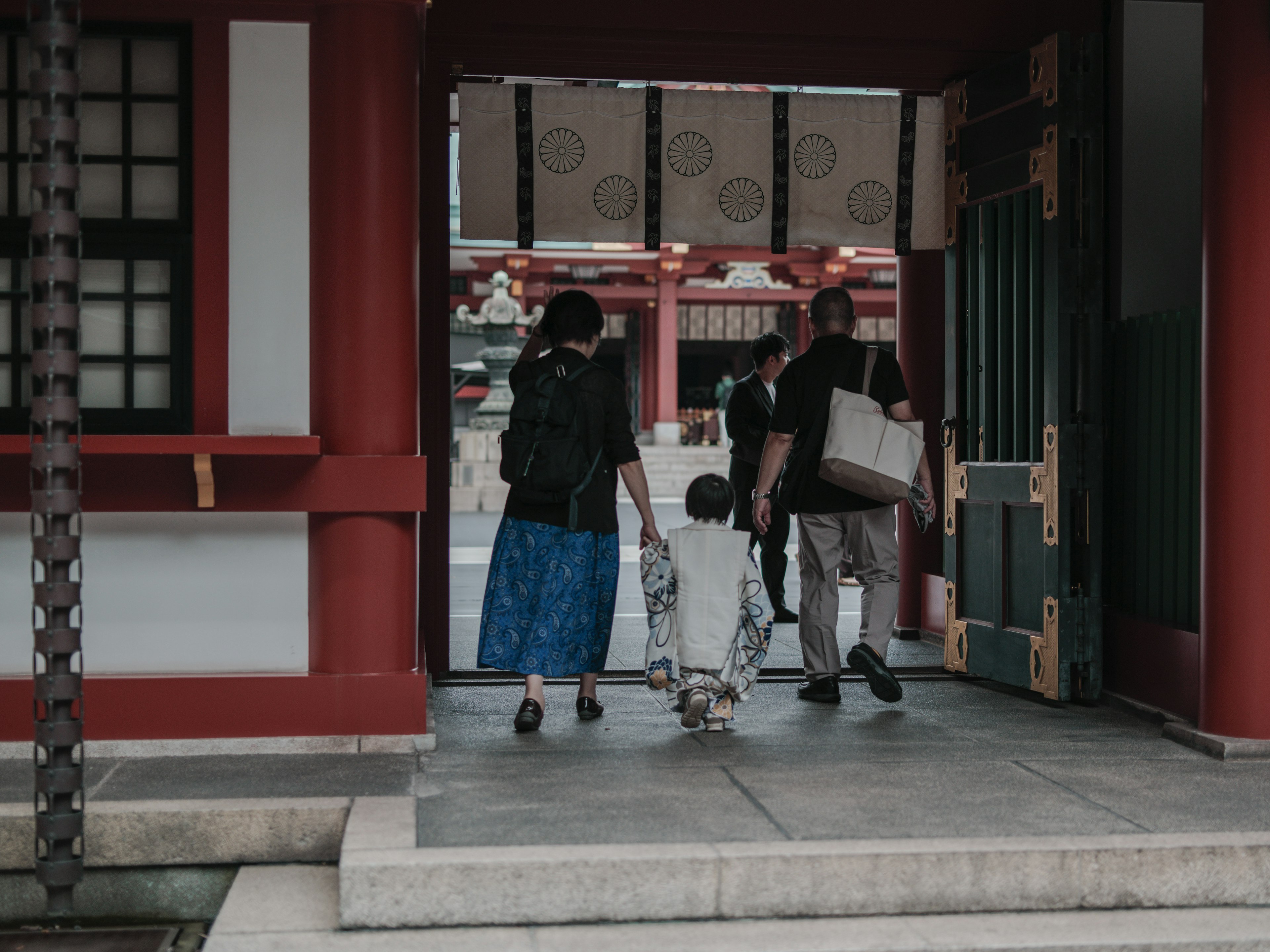 人們走過一個紅色建築的神社入口