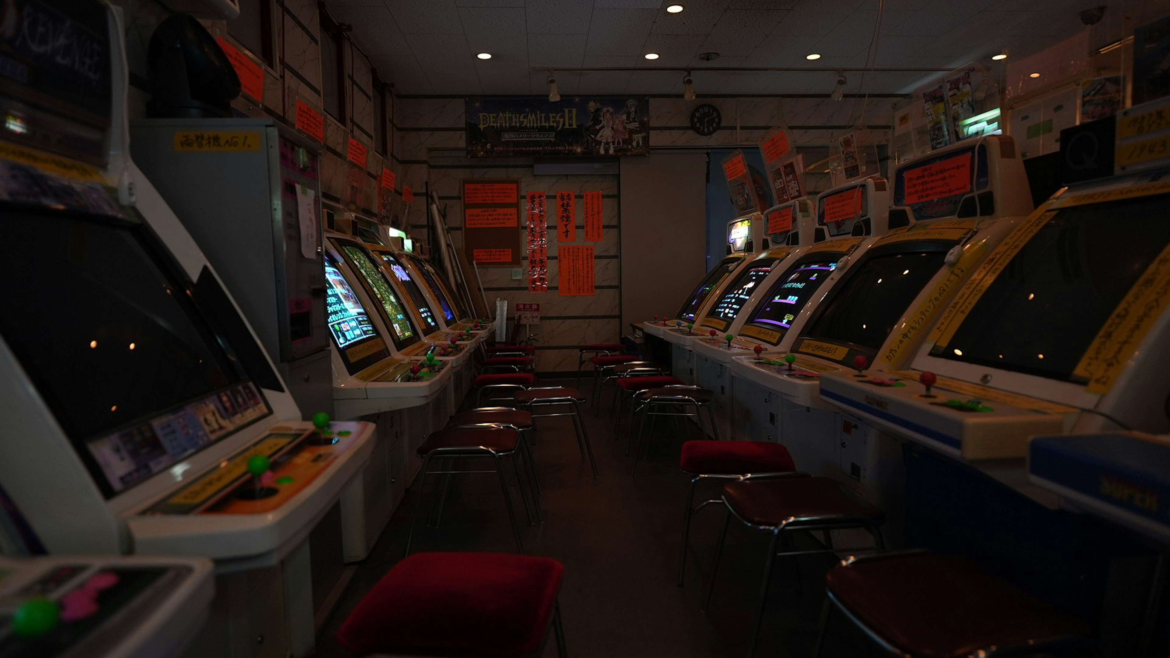 Dimly lit arcade featuring rows of vintage arcade game machines