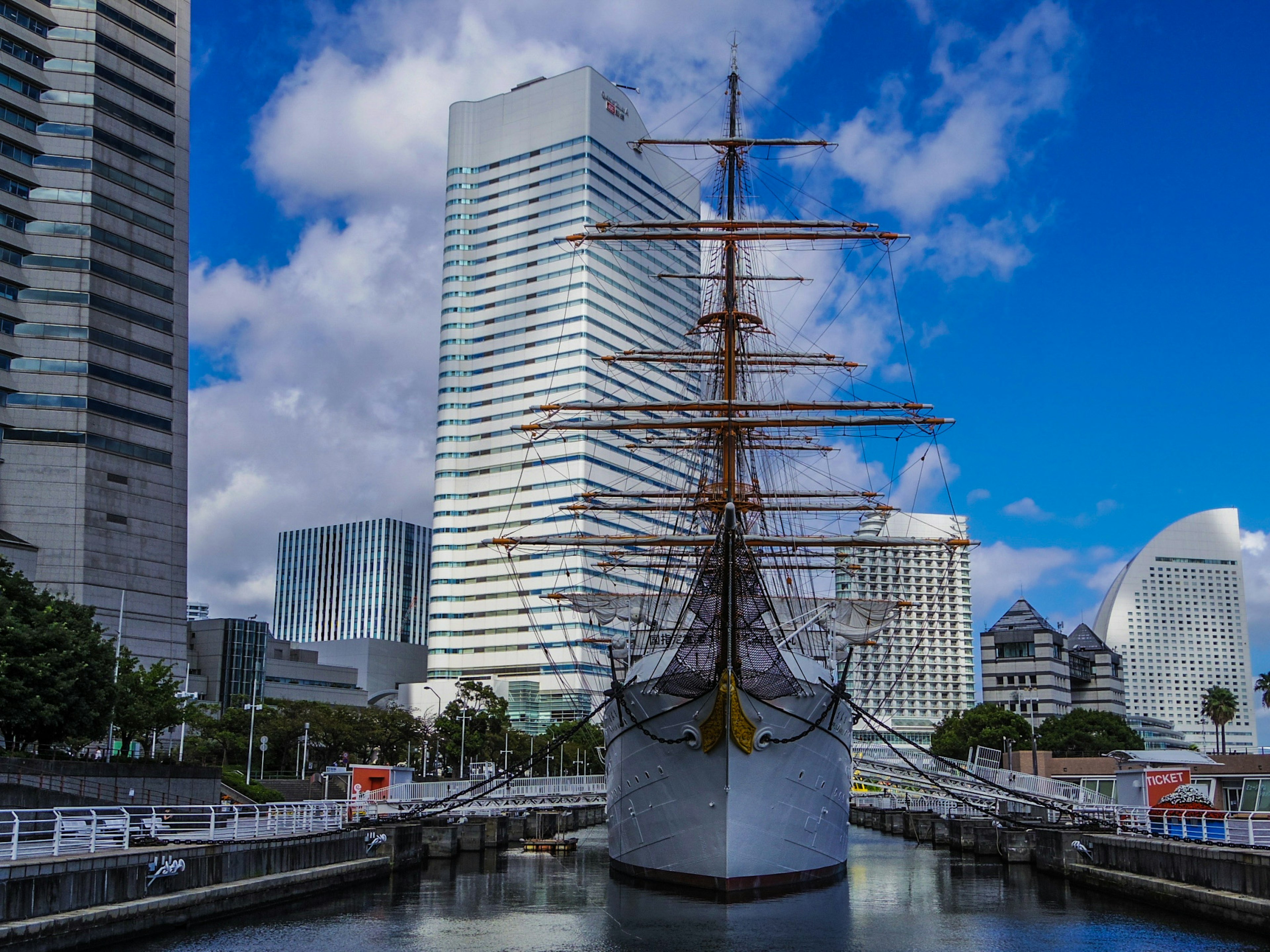 Historic sailing ship docked in Yokohama with modern skyscrapers