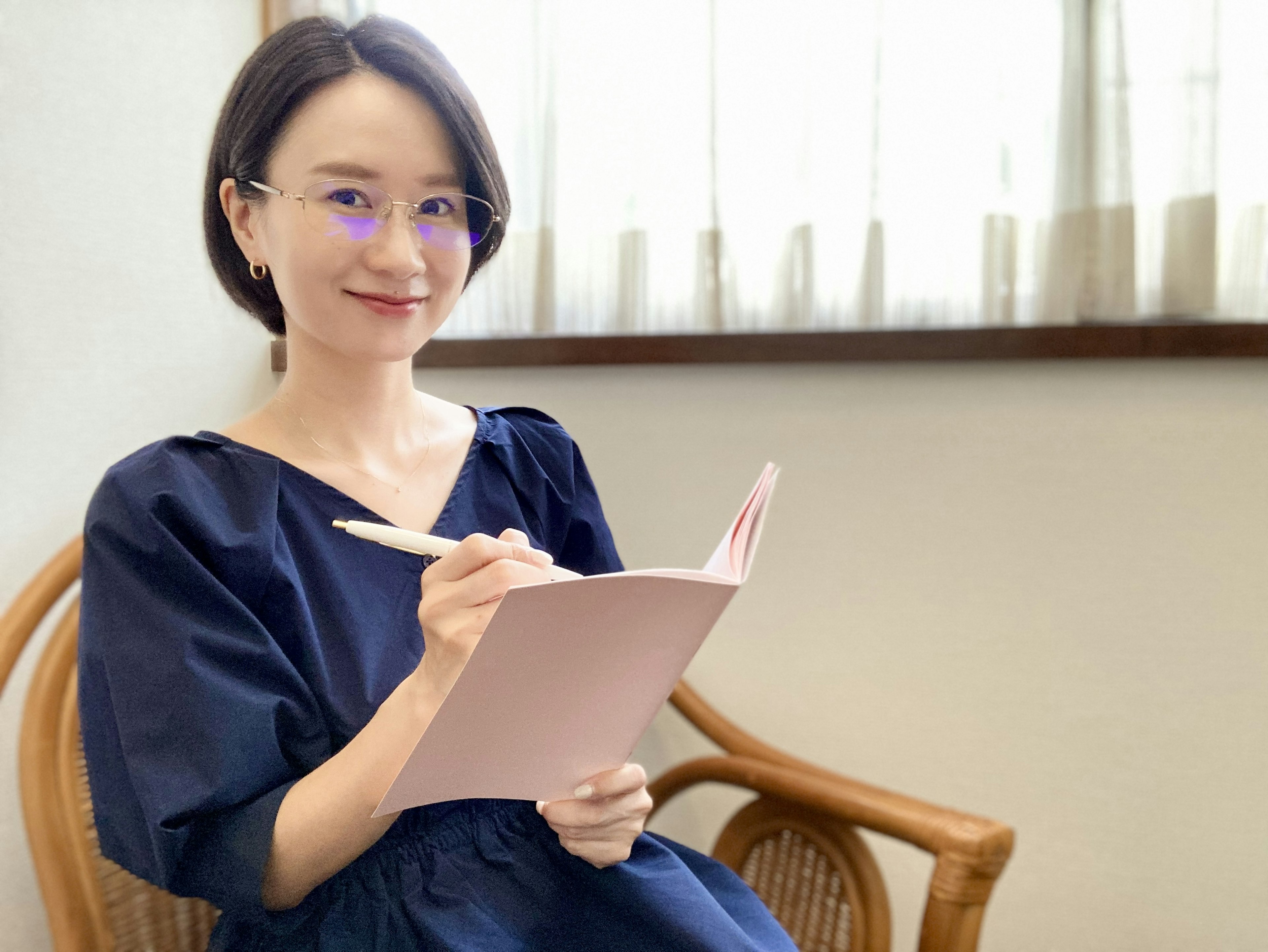 Une femme en robe bleue écrivant dans un carnet rose