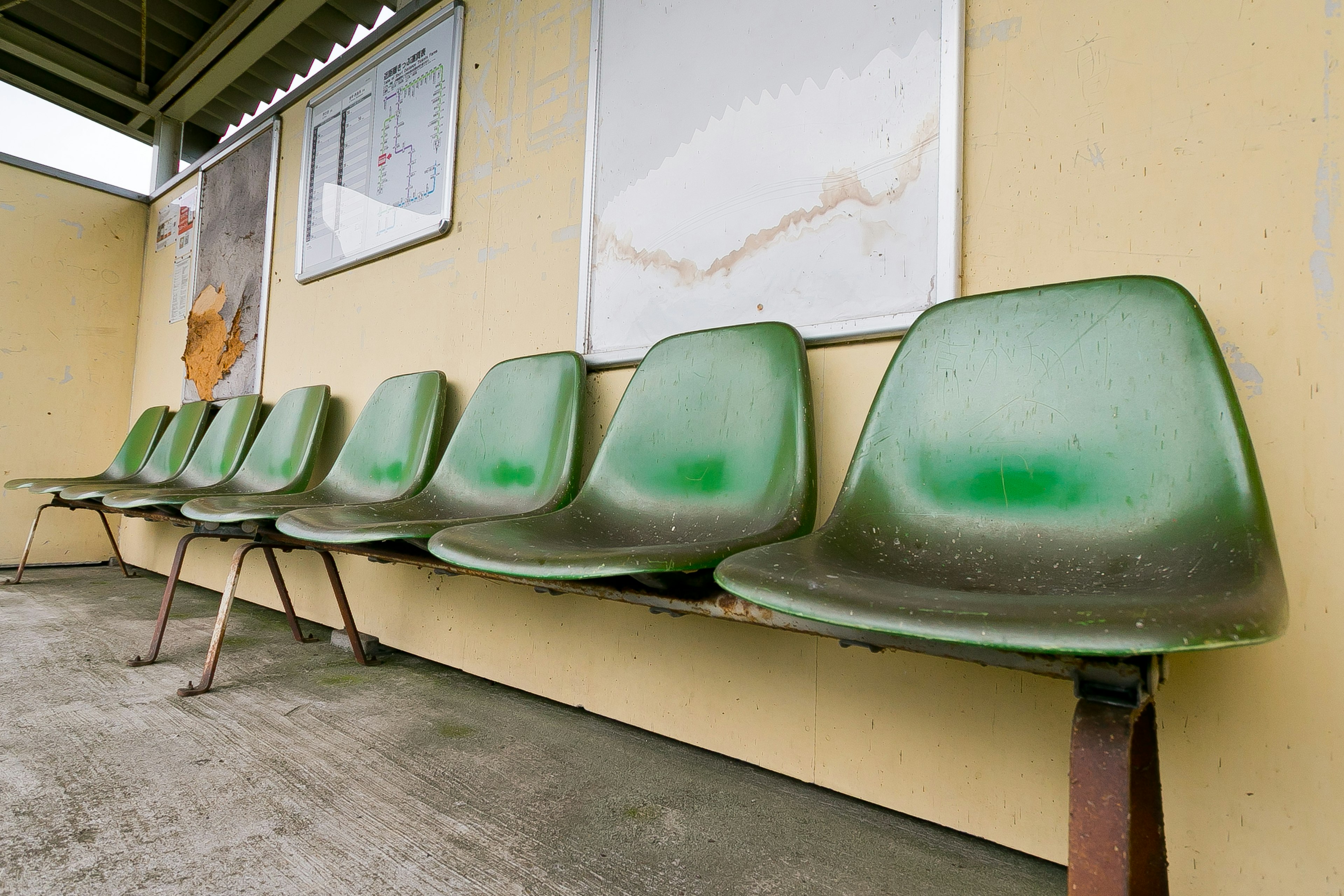 Row of old green plastic benches in a waiting area