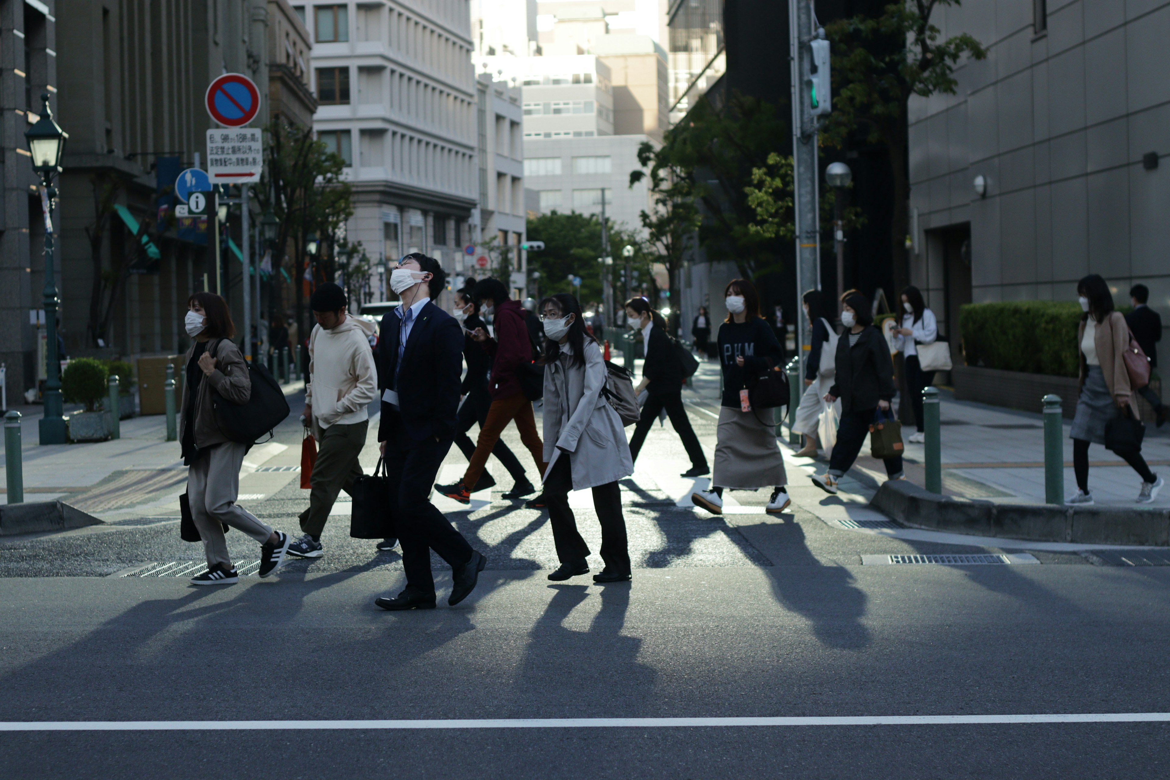 街を横断する人々の群れ 日差しが差し込む都市風景